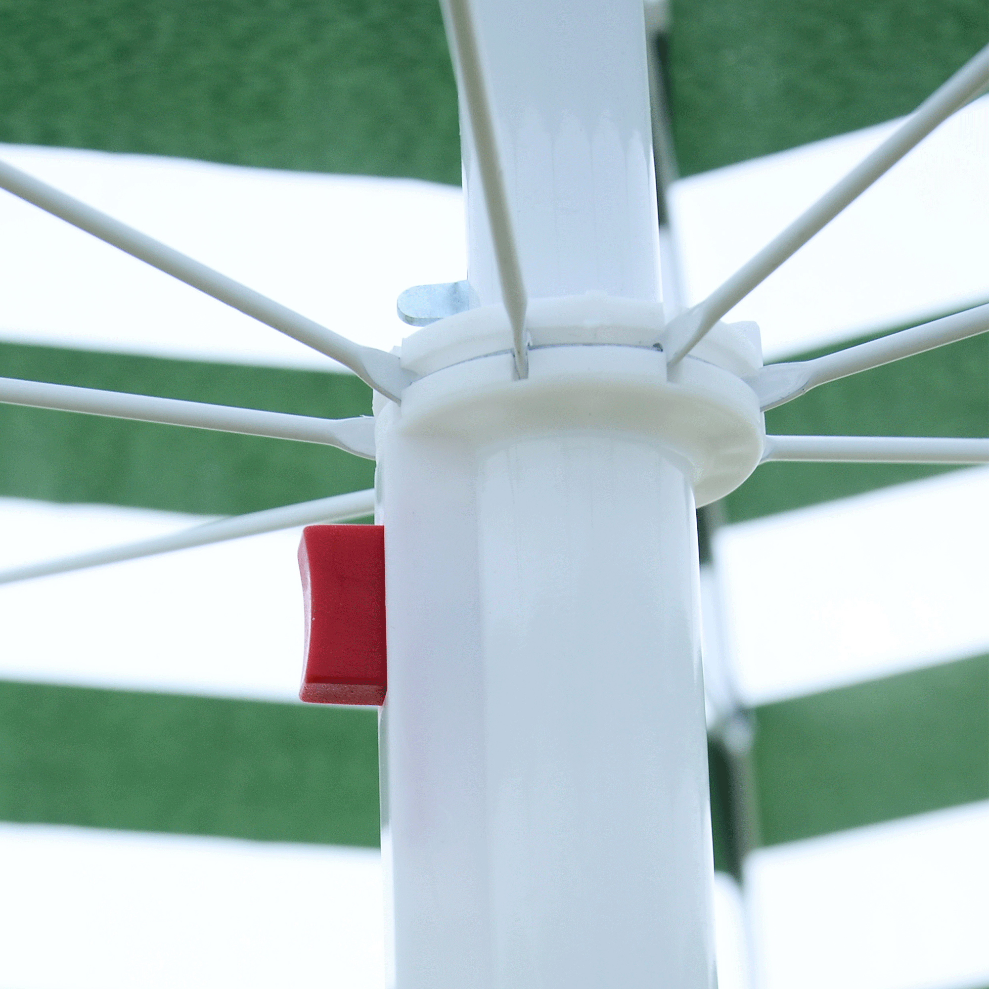 Primer plano de un paraguas blanco con botón rojo y rayas verdes.