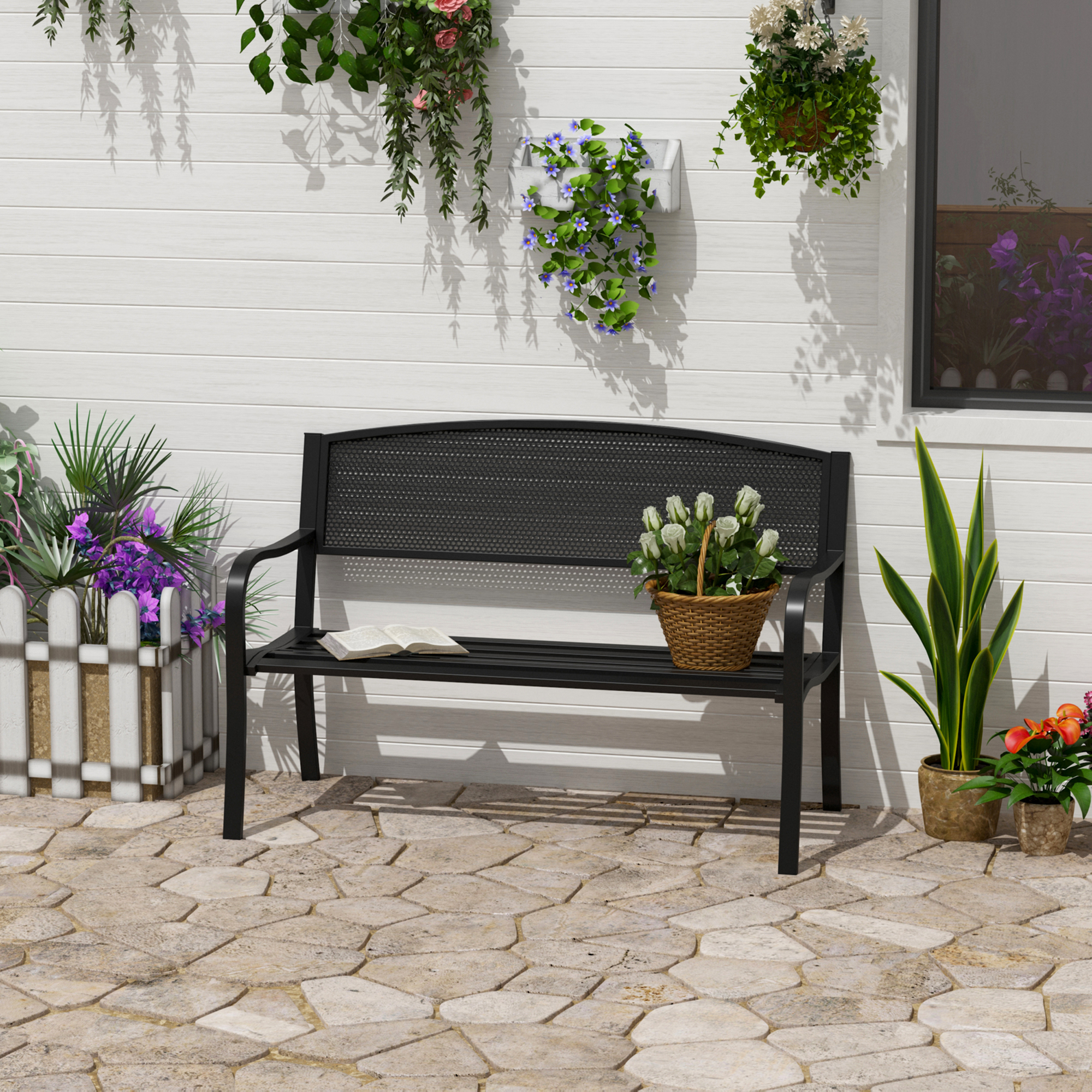 Una panchina nera siede su un patio di pietra di fronte a un muro di legno bianco con piante.