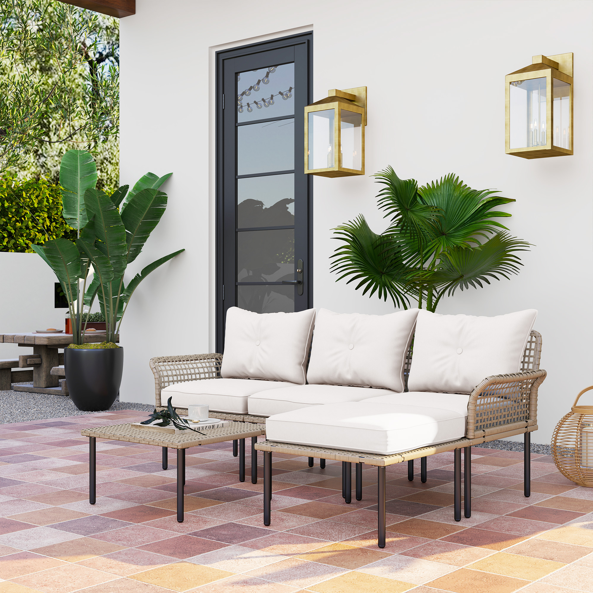 Un sofá de mimbre beige con cojines blancos está en un patio embaldosado.