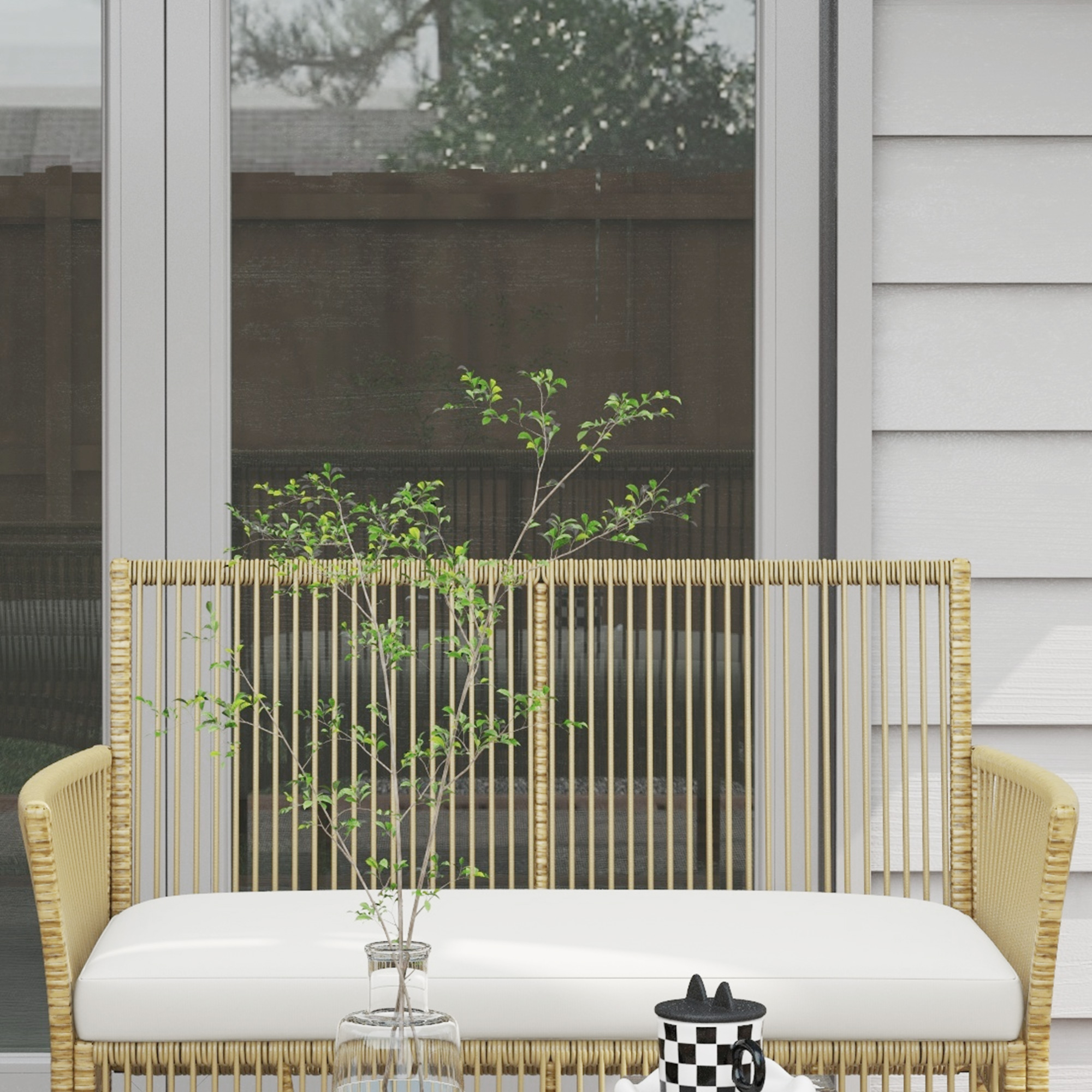 Una seduta moderna in rattan con cuscino bianco e una pianta in vaso.