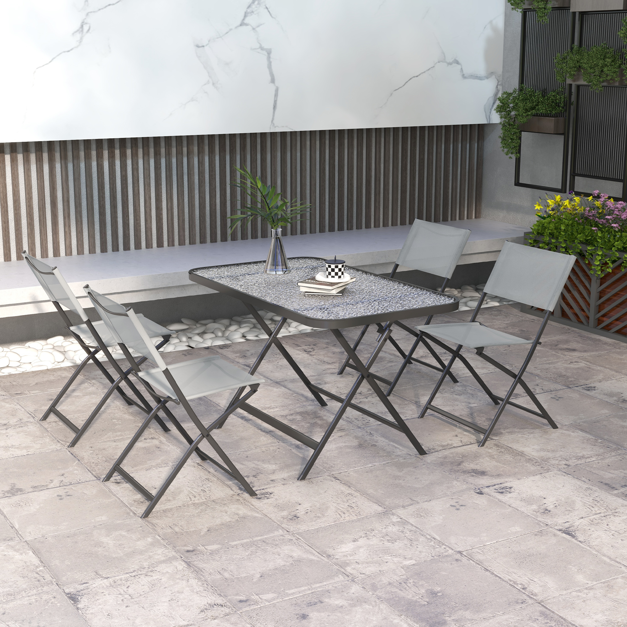 Un tavolo da esterno con quattro sedie su un patio di pietra, decorato con piante.