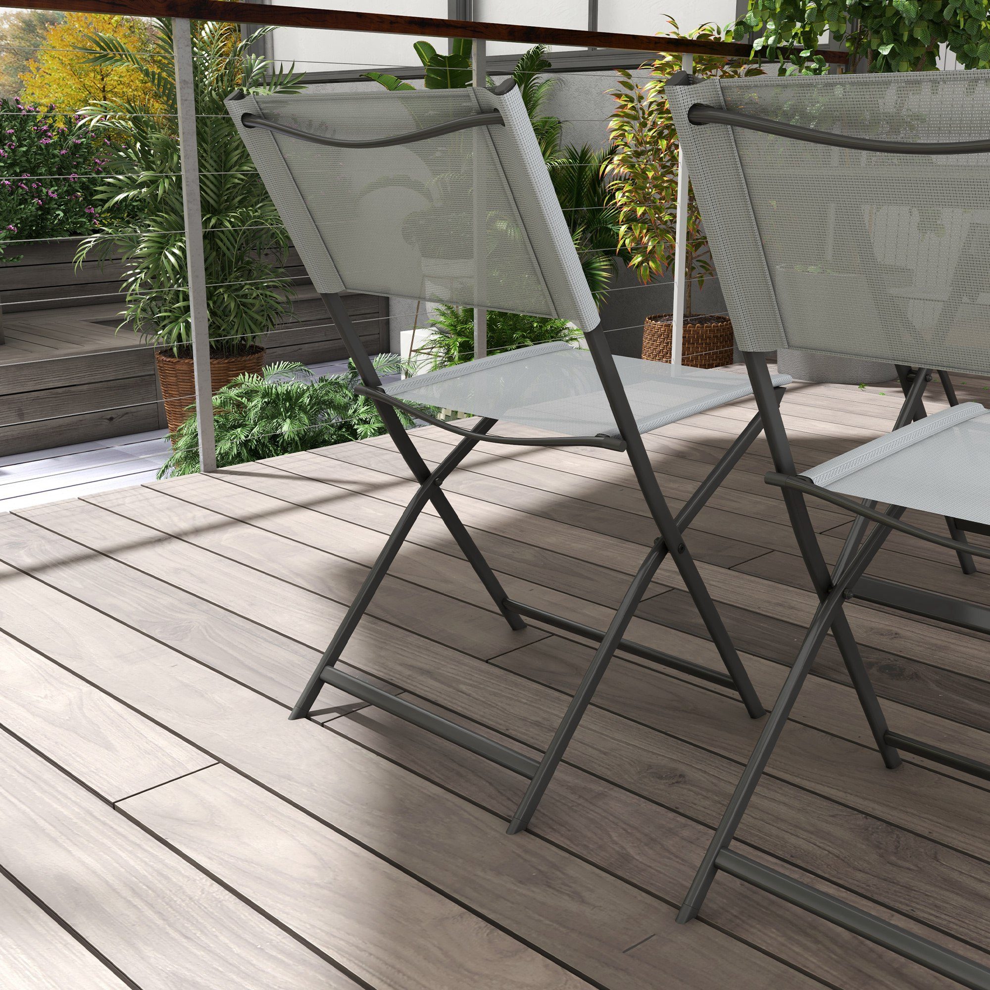 Sedie pieghevoli grigie su terrazza in legno con piante sullo sfondo.
