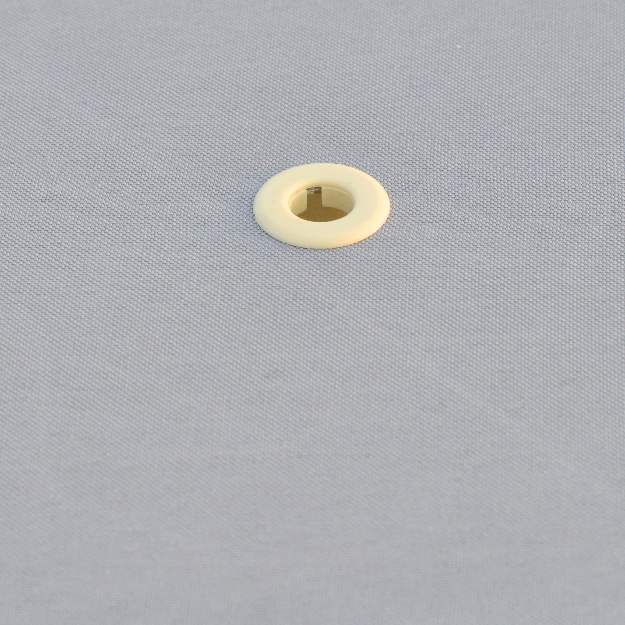 Un anillo color crema sobre tela gris.