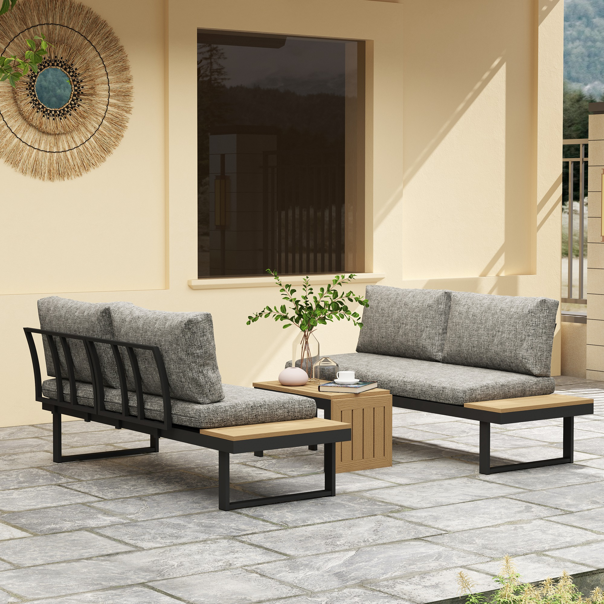 Muebles de exterior con cojines grises sobre un patio de piedra frente a un edificio beige.