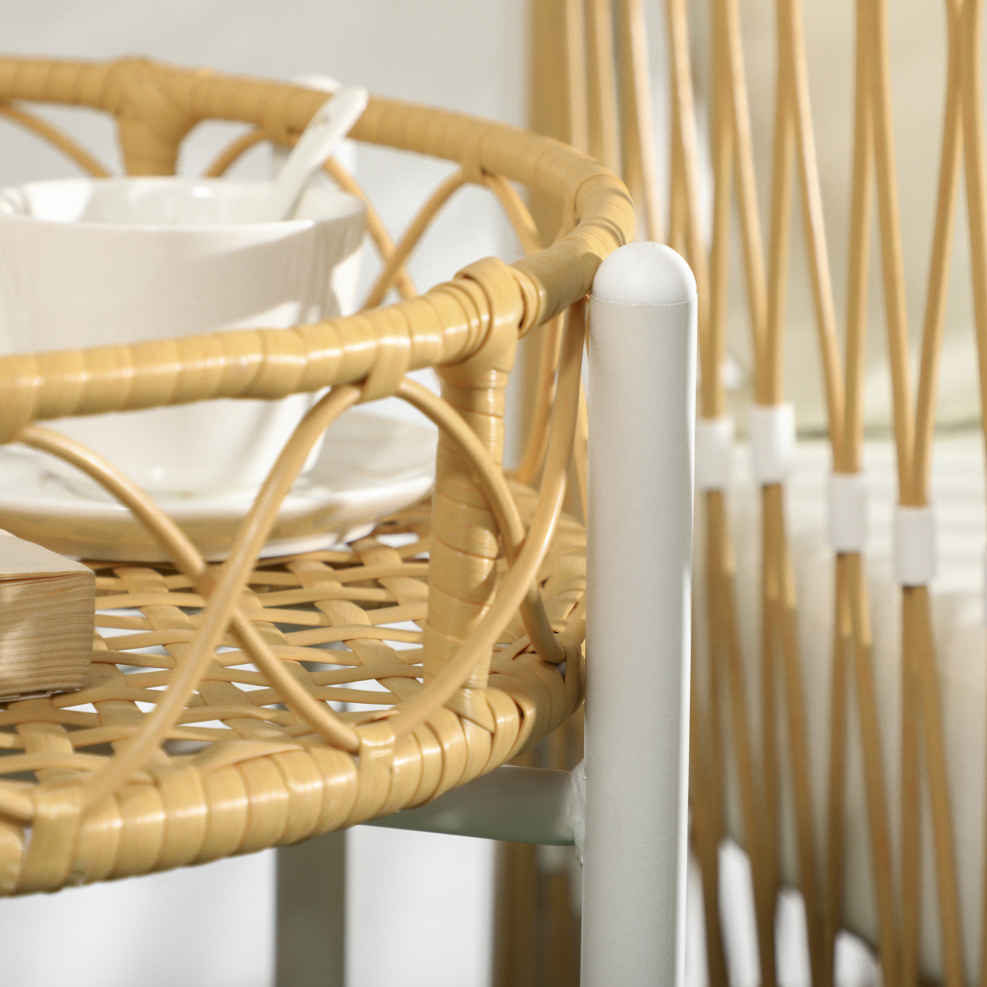Una tazza e un piattino bianchi su un vassoio di vimini accanto a uno scaffale bianco.