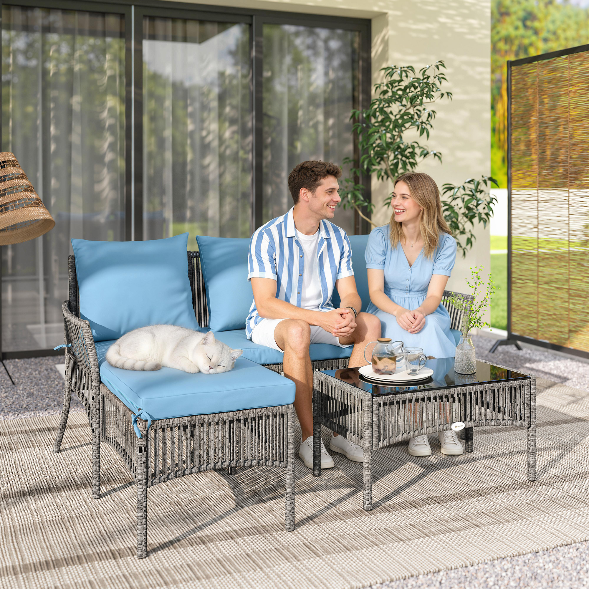 Una pareja se sienta en un sofá con un gato durmiendo. Una mesa con té está delante.