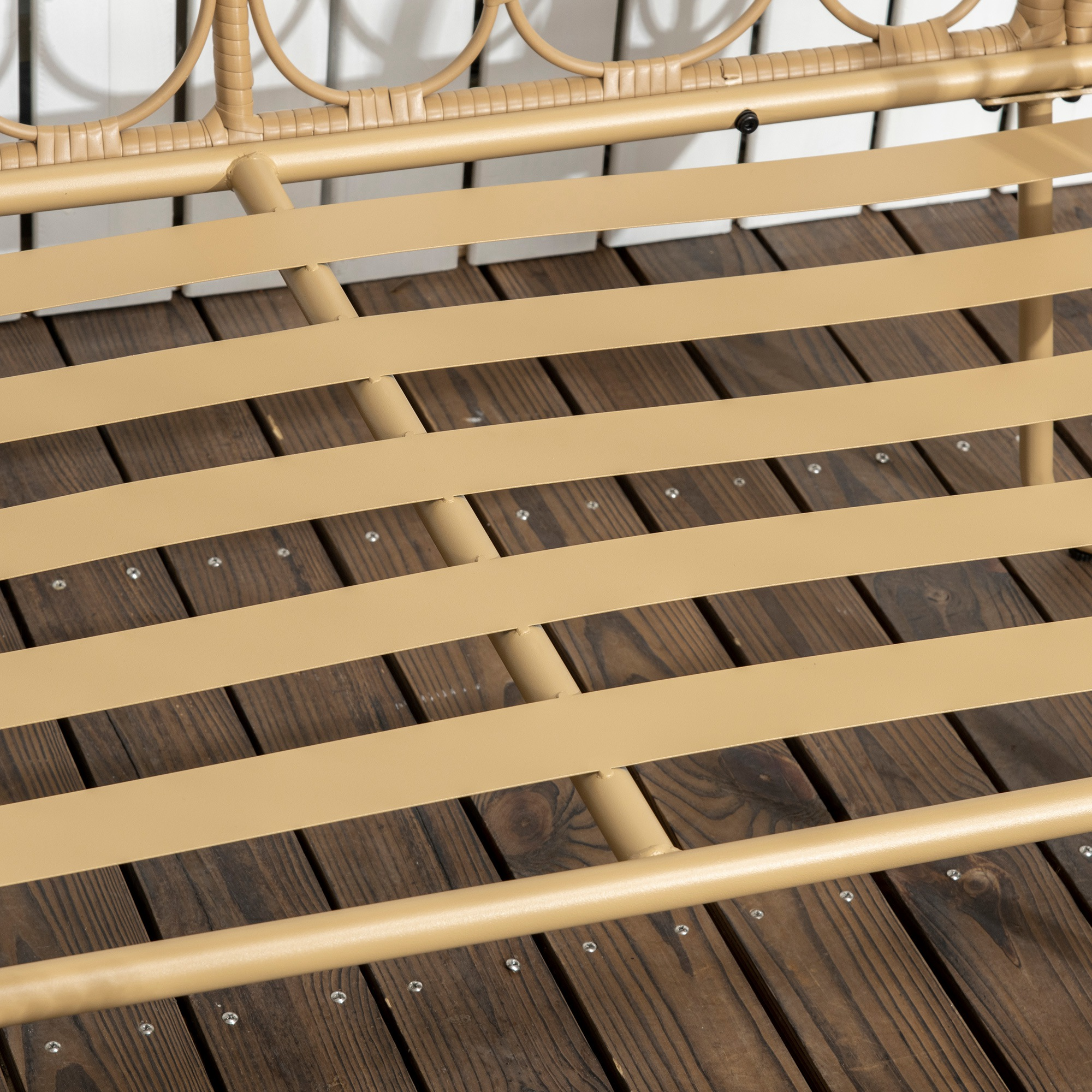 Primer plano de una base de cama de metal beige con lamas sobre tablones de madera.