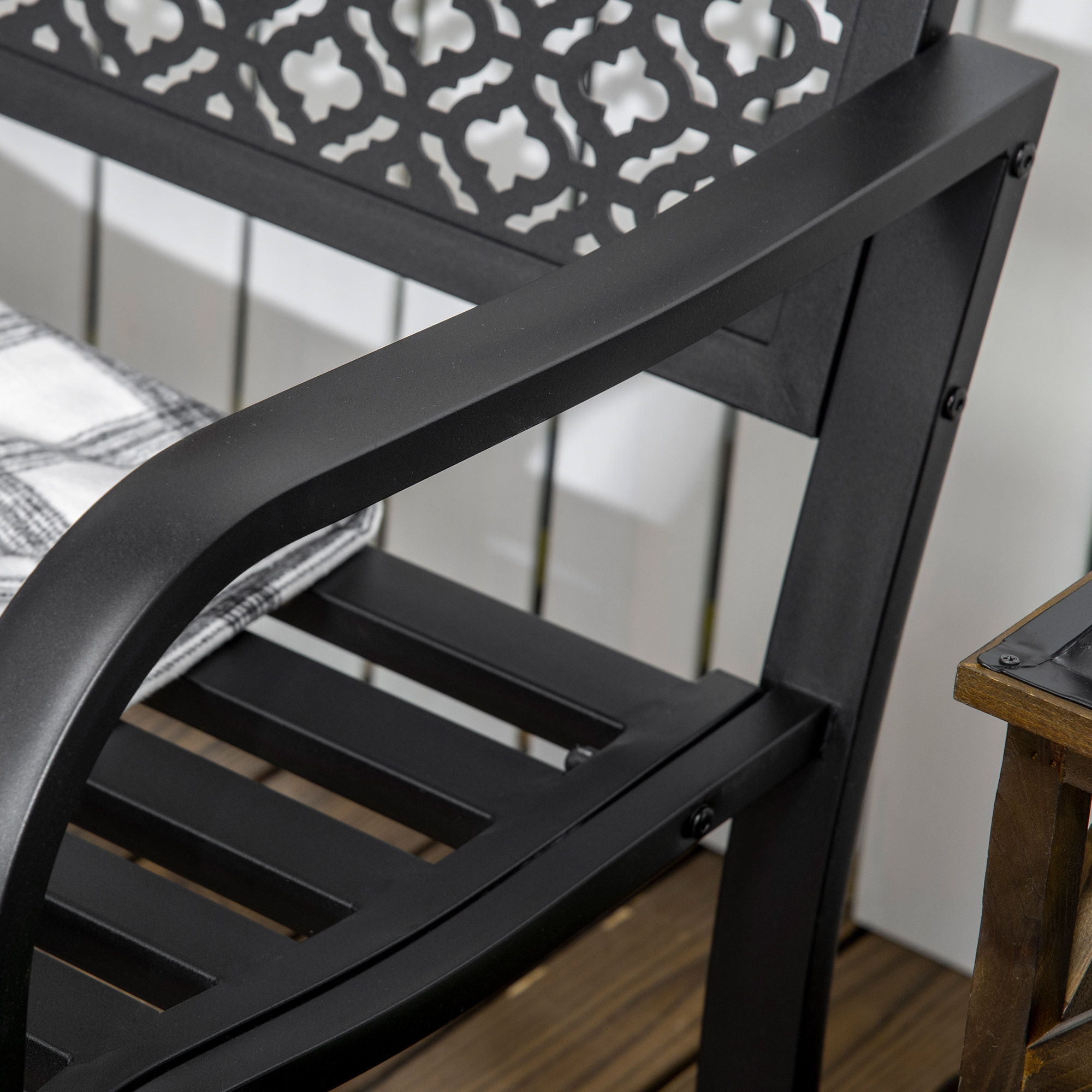Silla negra con cojín a cuadros sobre tablones de madera.