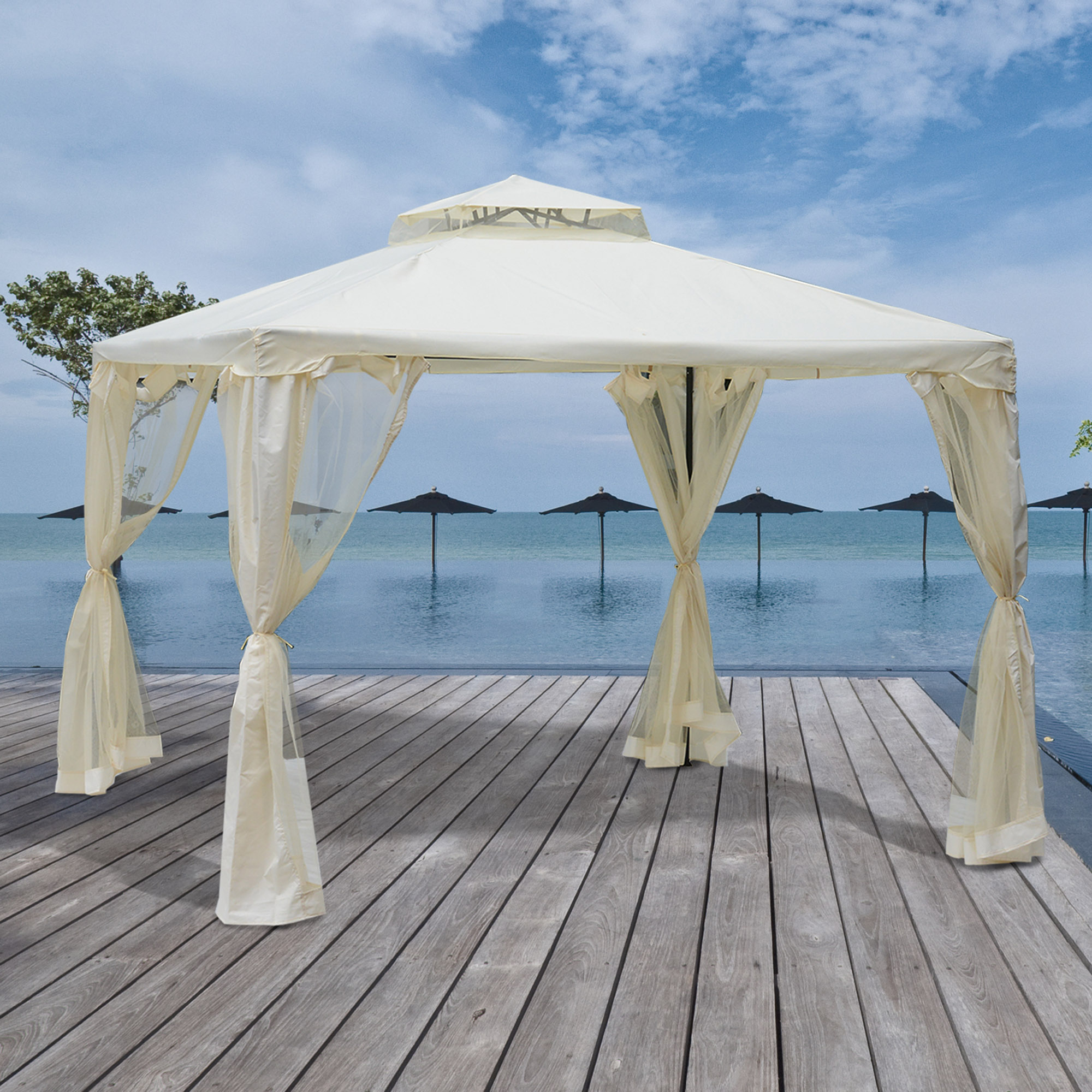 Un cenador beige sobre una terraza de madera junto a una piscina con vistas al mar.