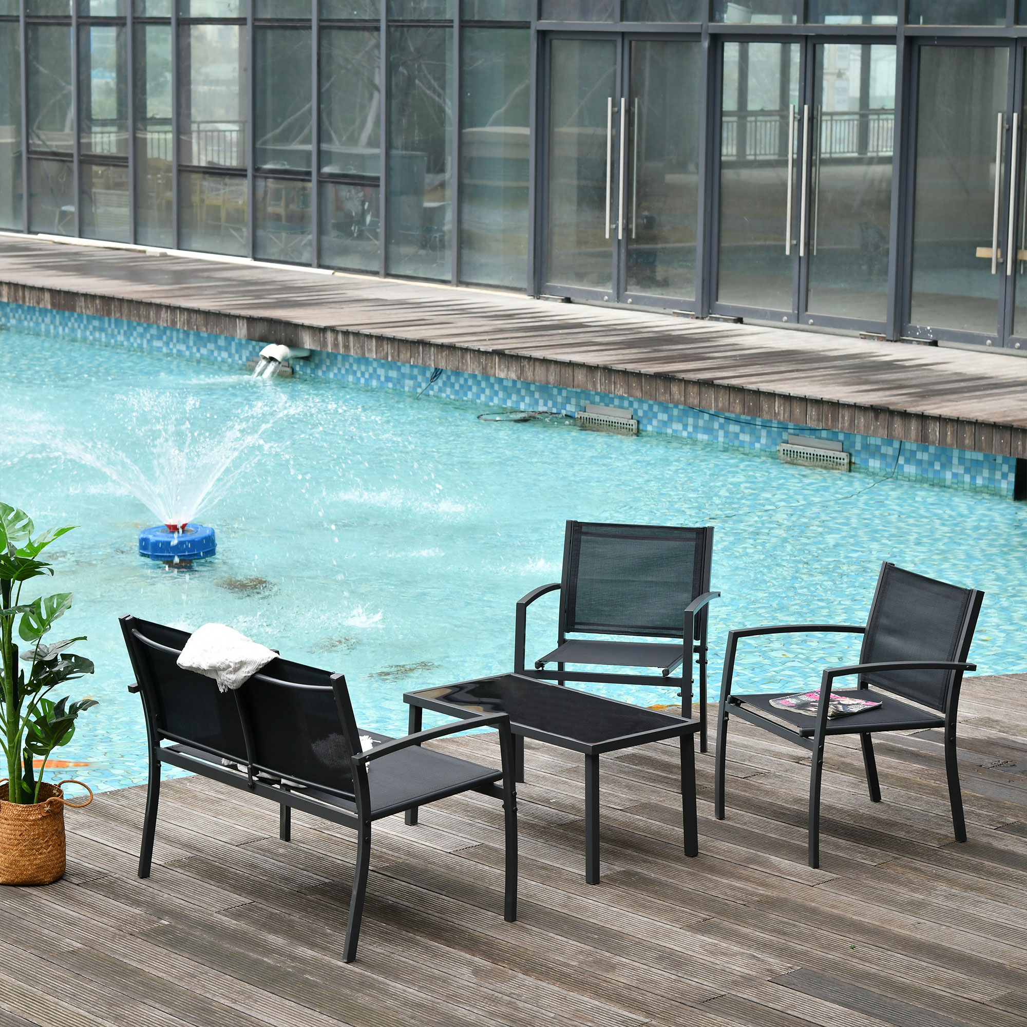 Mobili da giardino vicino a una piscina con fontana ed edificio sullo sfondo.