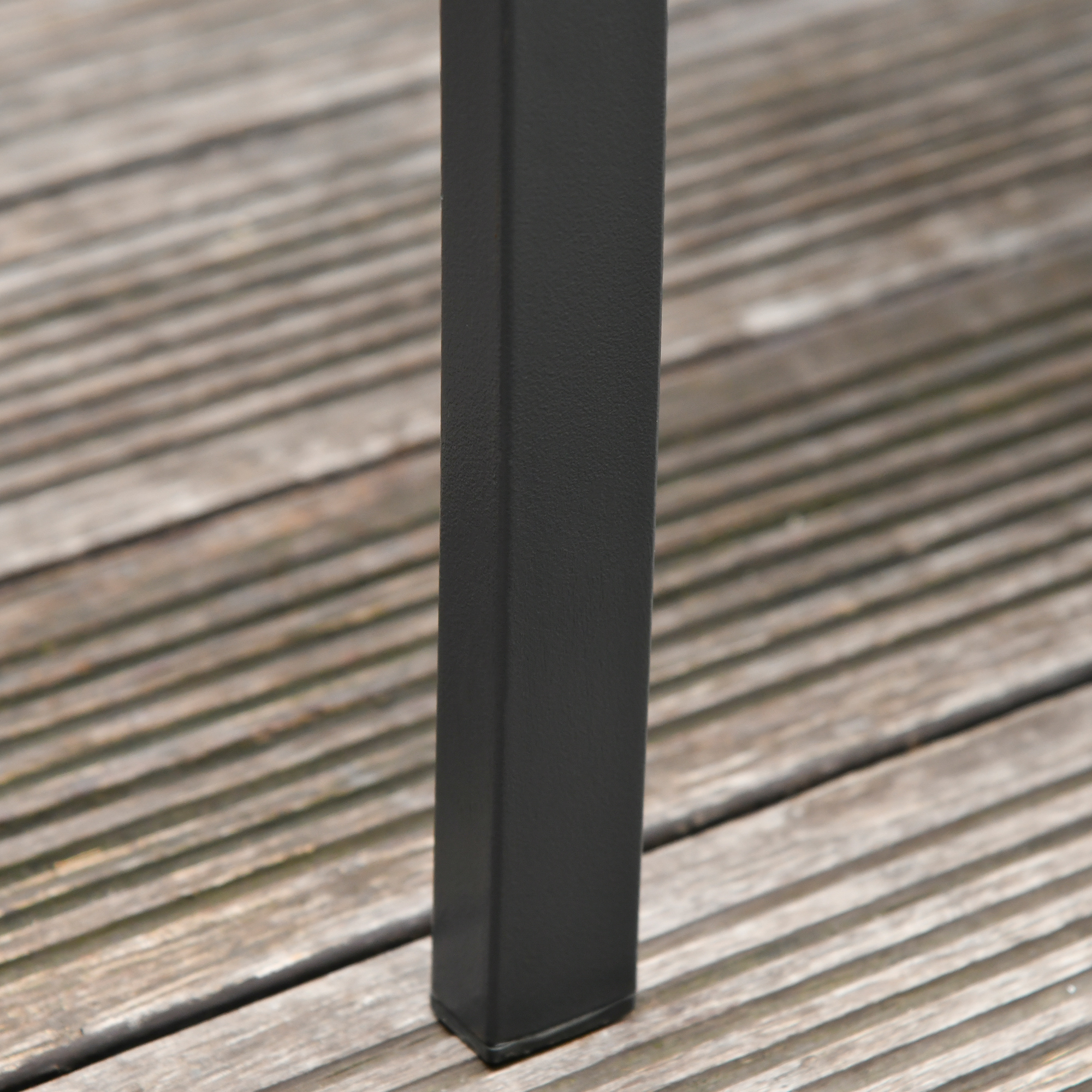 Una gamba in metallo nero si trova su un ponte di legno.