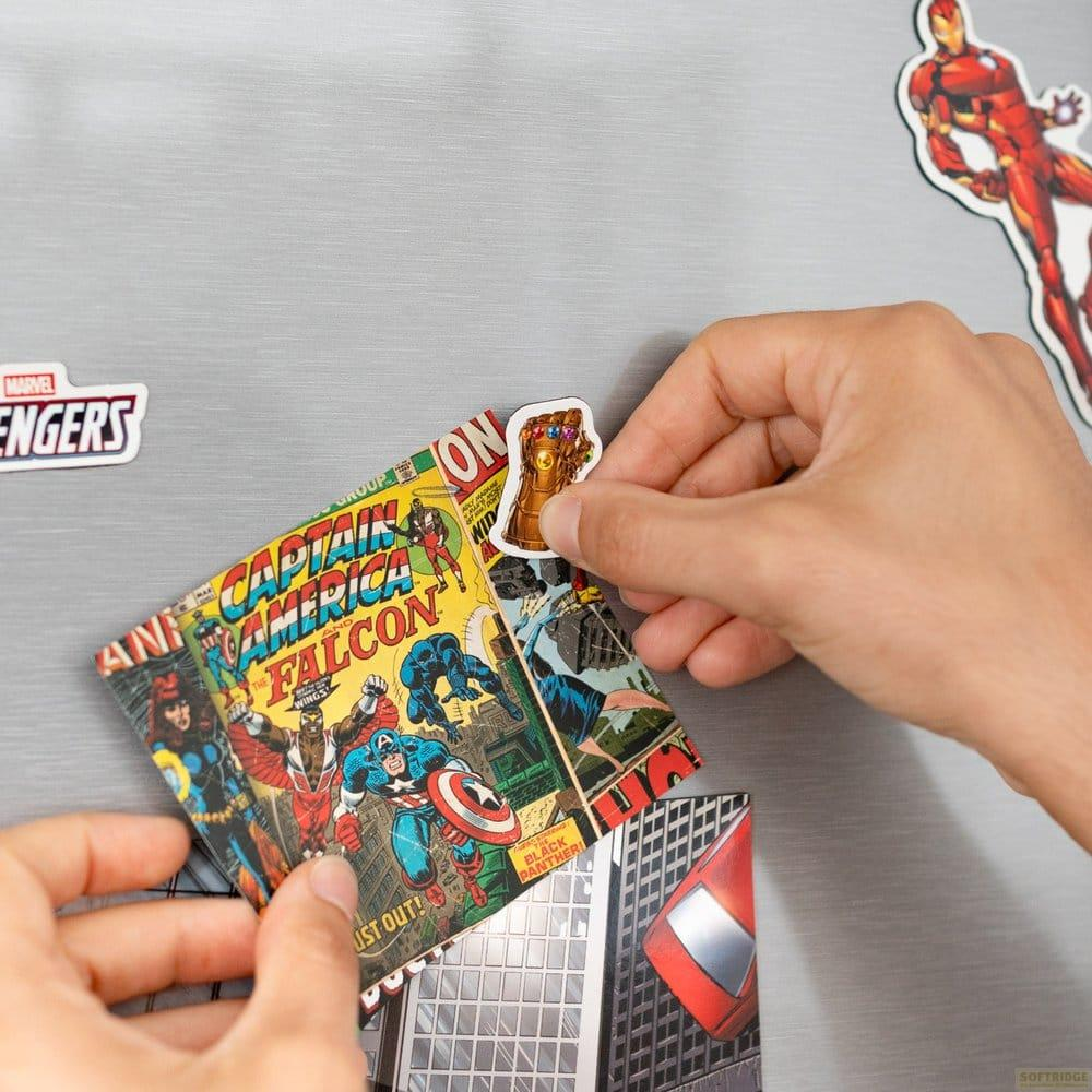 Hände platzieren Marvel-Comic-Aufkleber von Captain America und Infinity Gauntlet auf Kühlschrank.