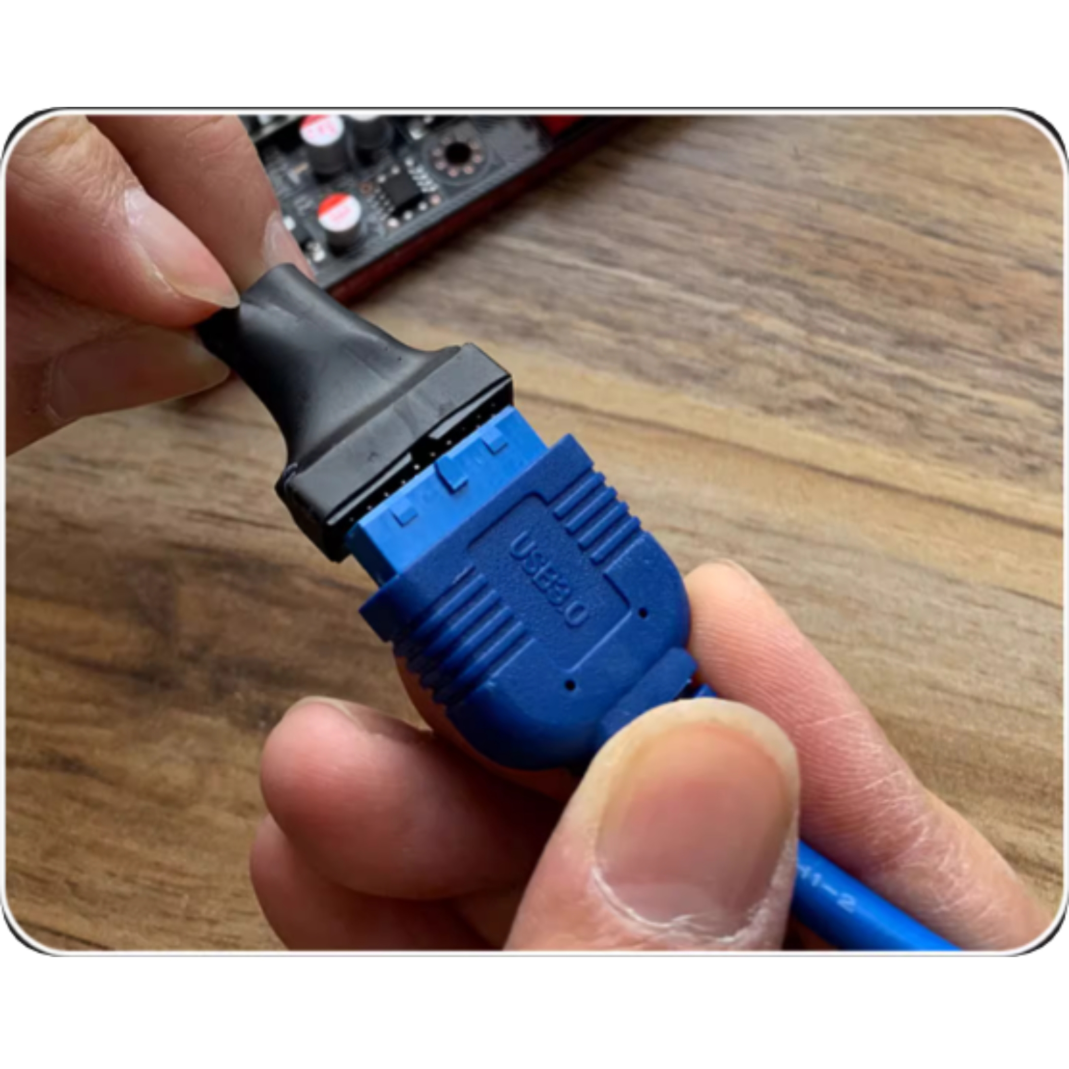 Hände verbinden ein blaues USB 3.0-Kabel mit einem schwarzen Stecker an einer Platine.