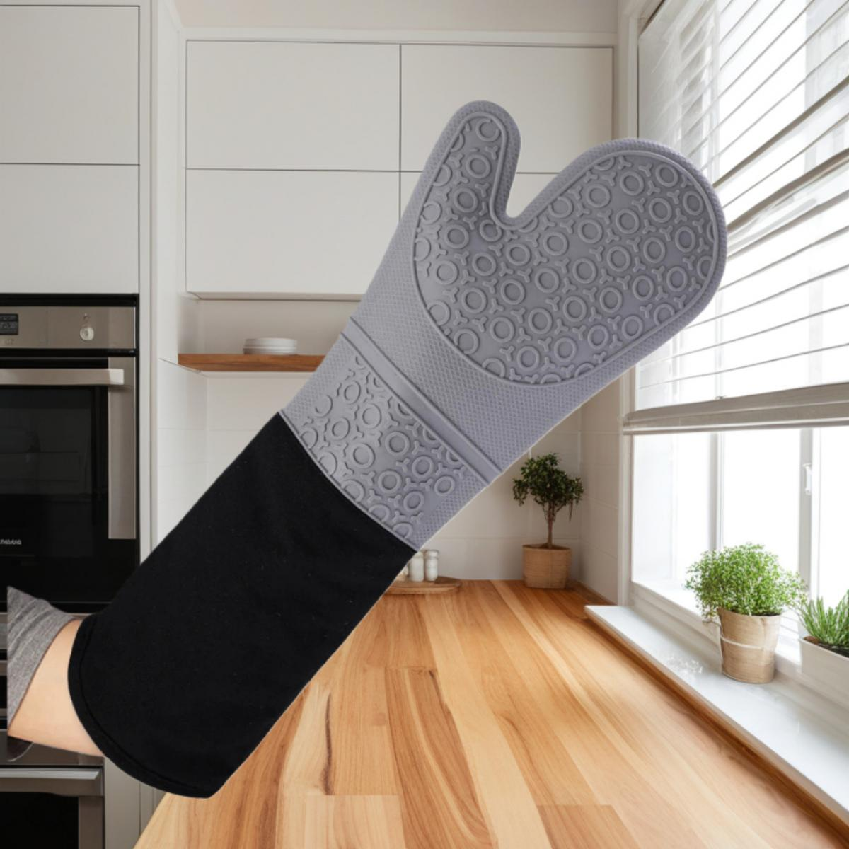Grauer Ofenhandschuh mit schwarzem Stoffärmel auf einer Küchenarbeitsplatte.