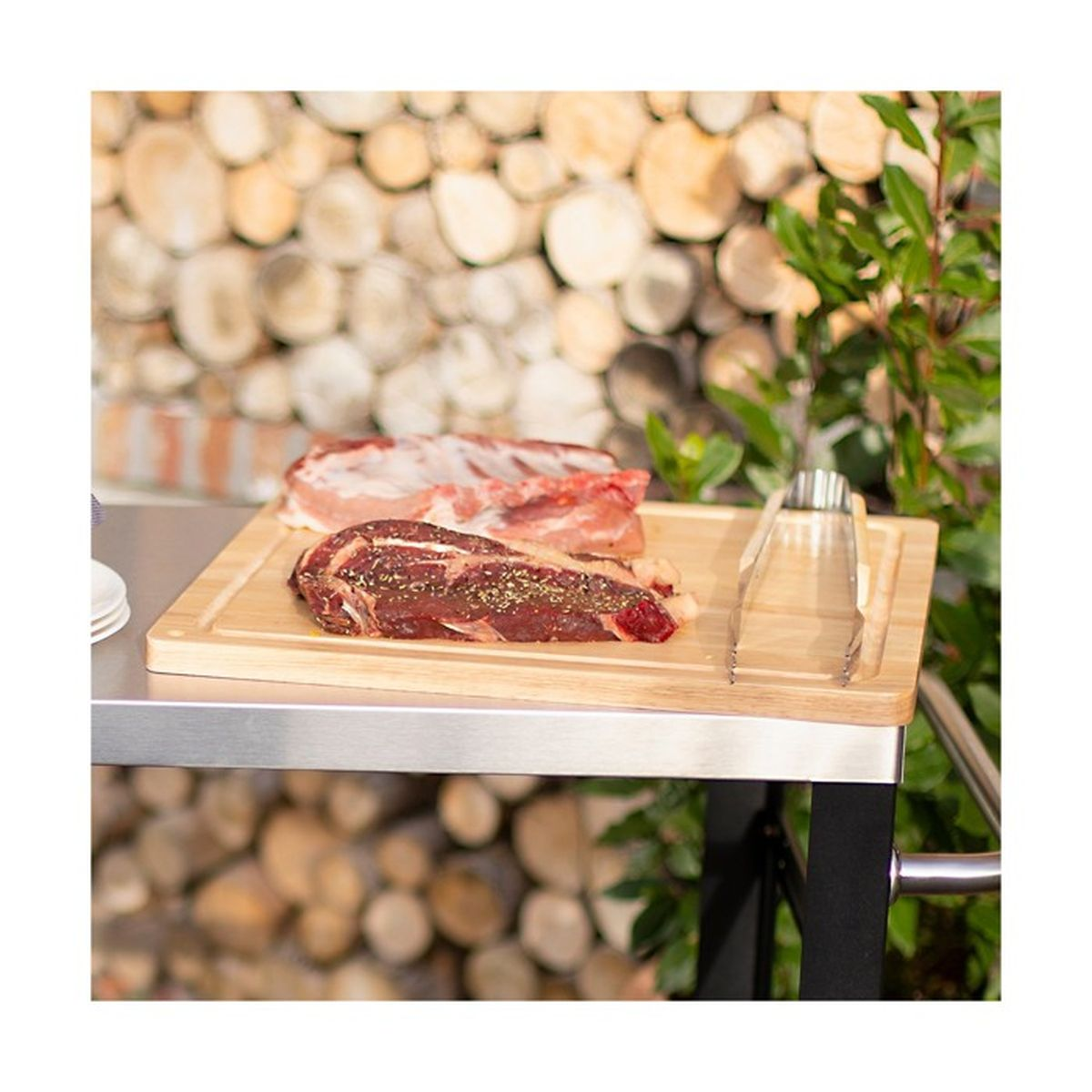 Rohes Fleisch auf einem Holzbrett, im Freien mit Holzstapeln im Hintergrund.