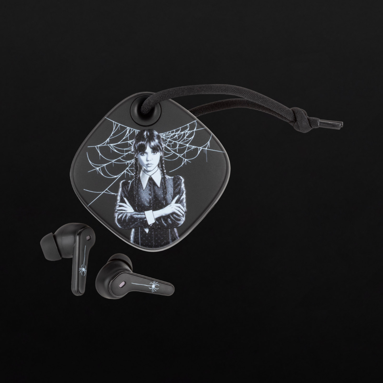 Czarny brelok z Wednesday Addams i pajęczyną, obok dwóch czarnych słuchawek.