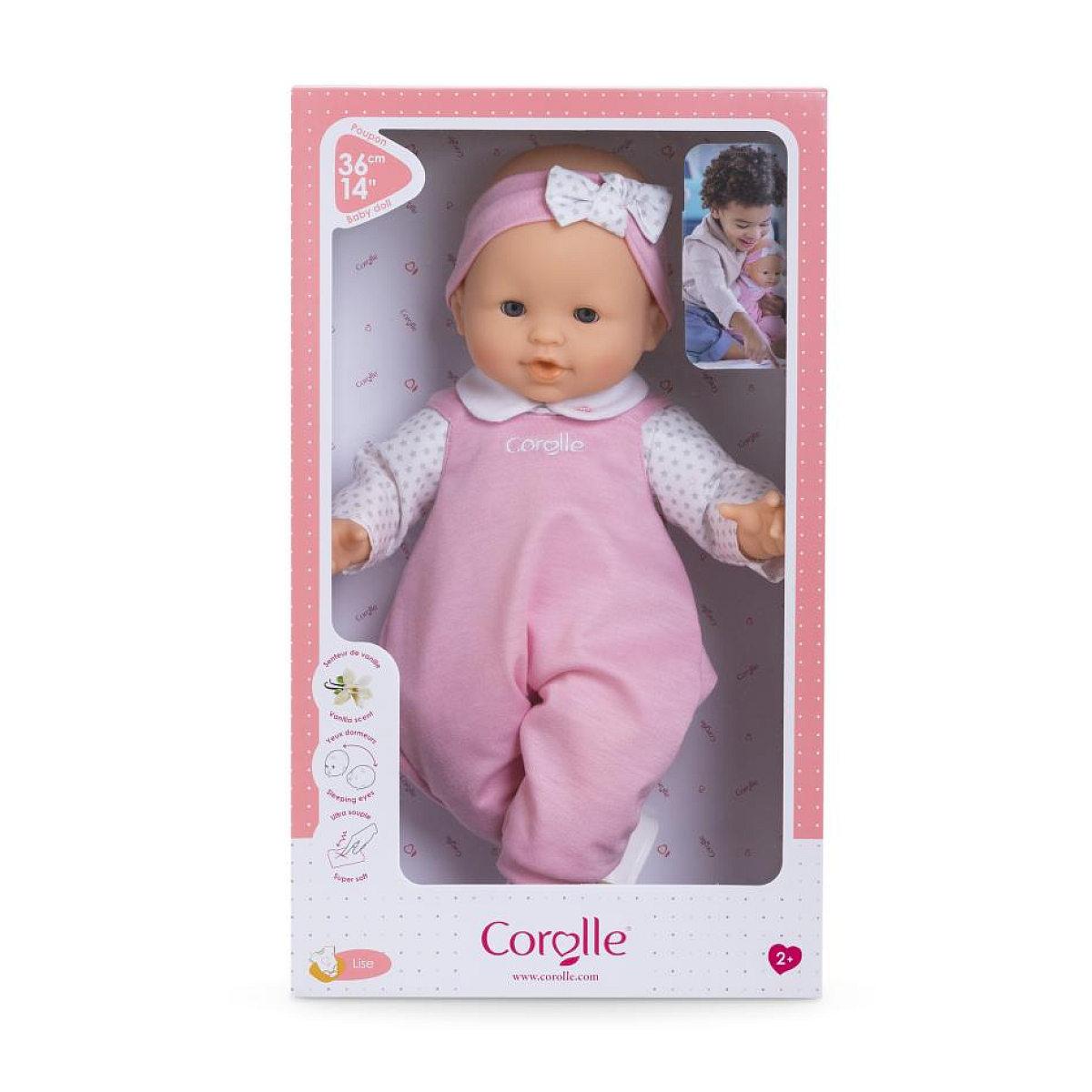 Eine 36cm große Babypuppe in einem rosa Strampler mit weißen Punkten und einem Stirnband mit Schleife.