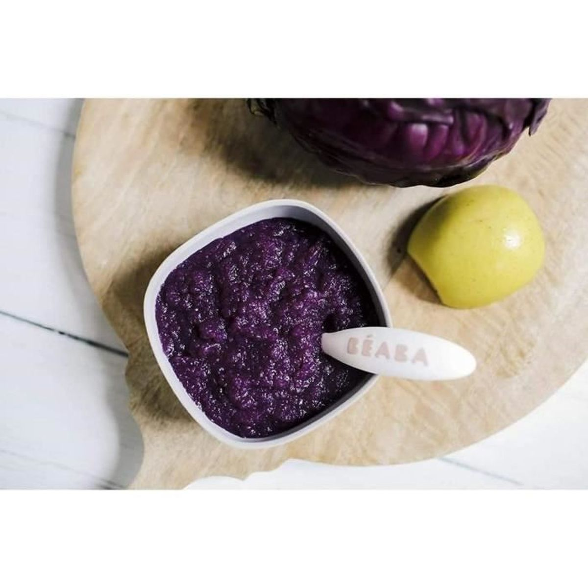 Purpurfarbene Breimahlzeit in einer Schüssel mit Apfel und Rotkohl.