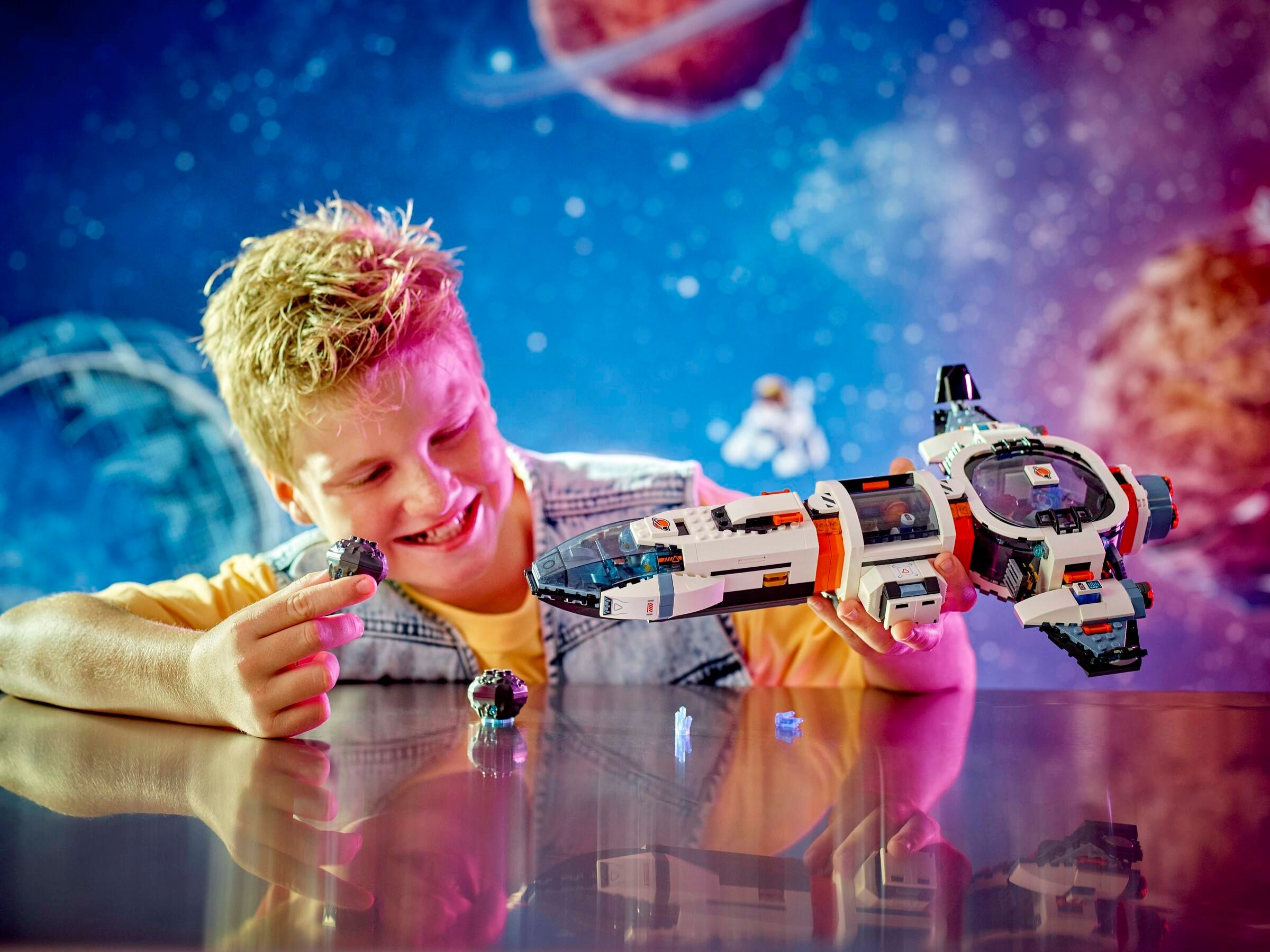 Junge mit Lego-Raumschiff und Steinen vor Weltraumhintergrund.