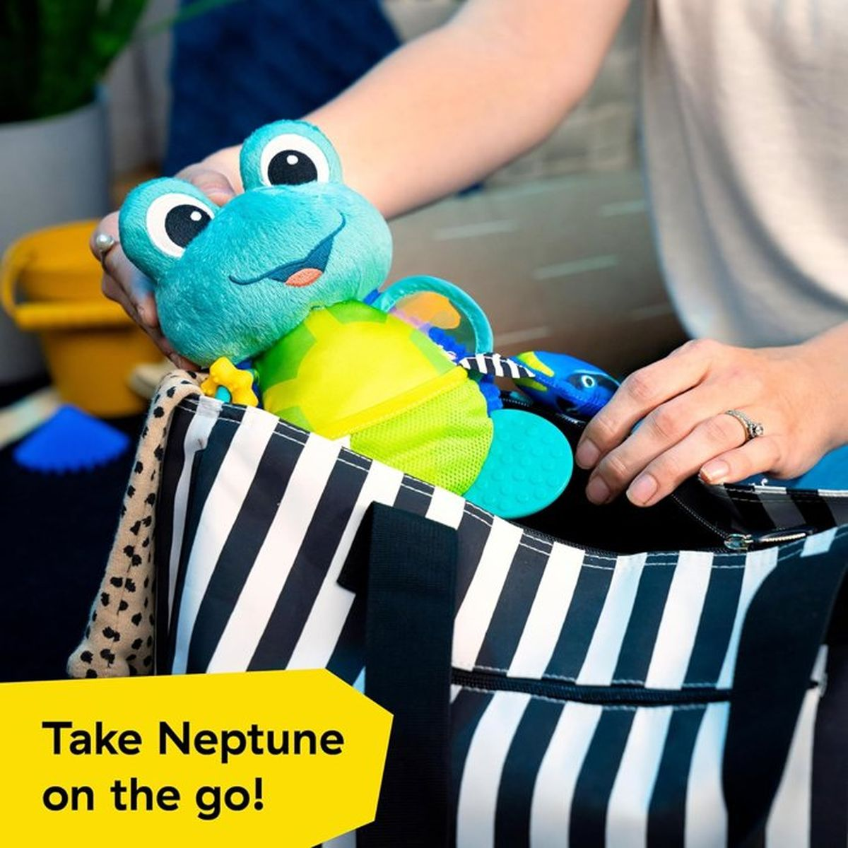 Ein blauer Froschspielzeug wird in eine schwarz-weiße Tasche gepackt.