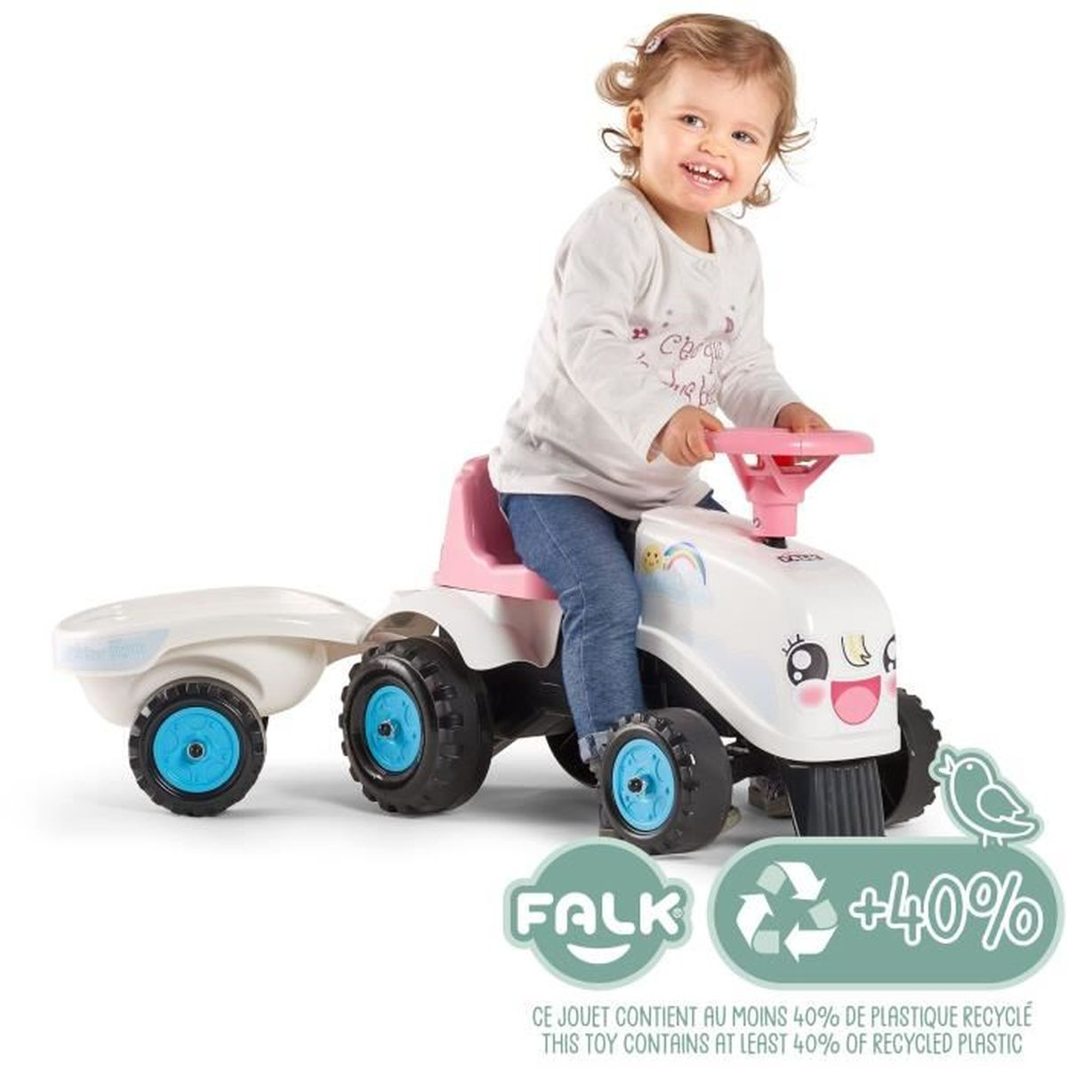 Ein kleines Mädchen fährt einen weißen Spielzeugtraktor mit Anhänger.