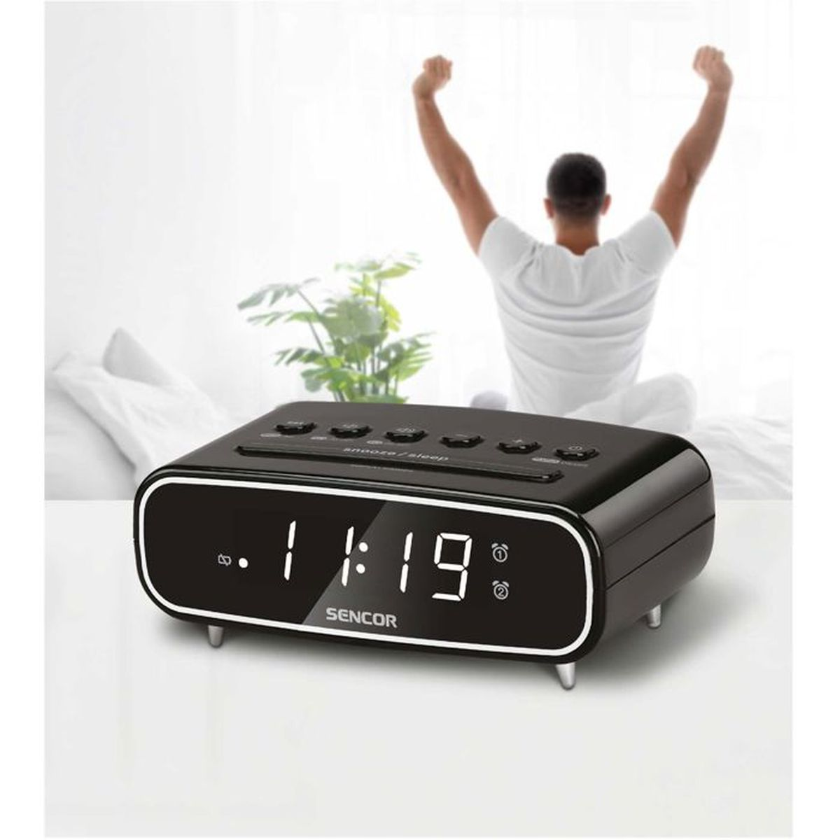 Ein Mann streckt sich im Bett, ein Radiowecker steht im Vordergrund.