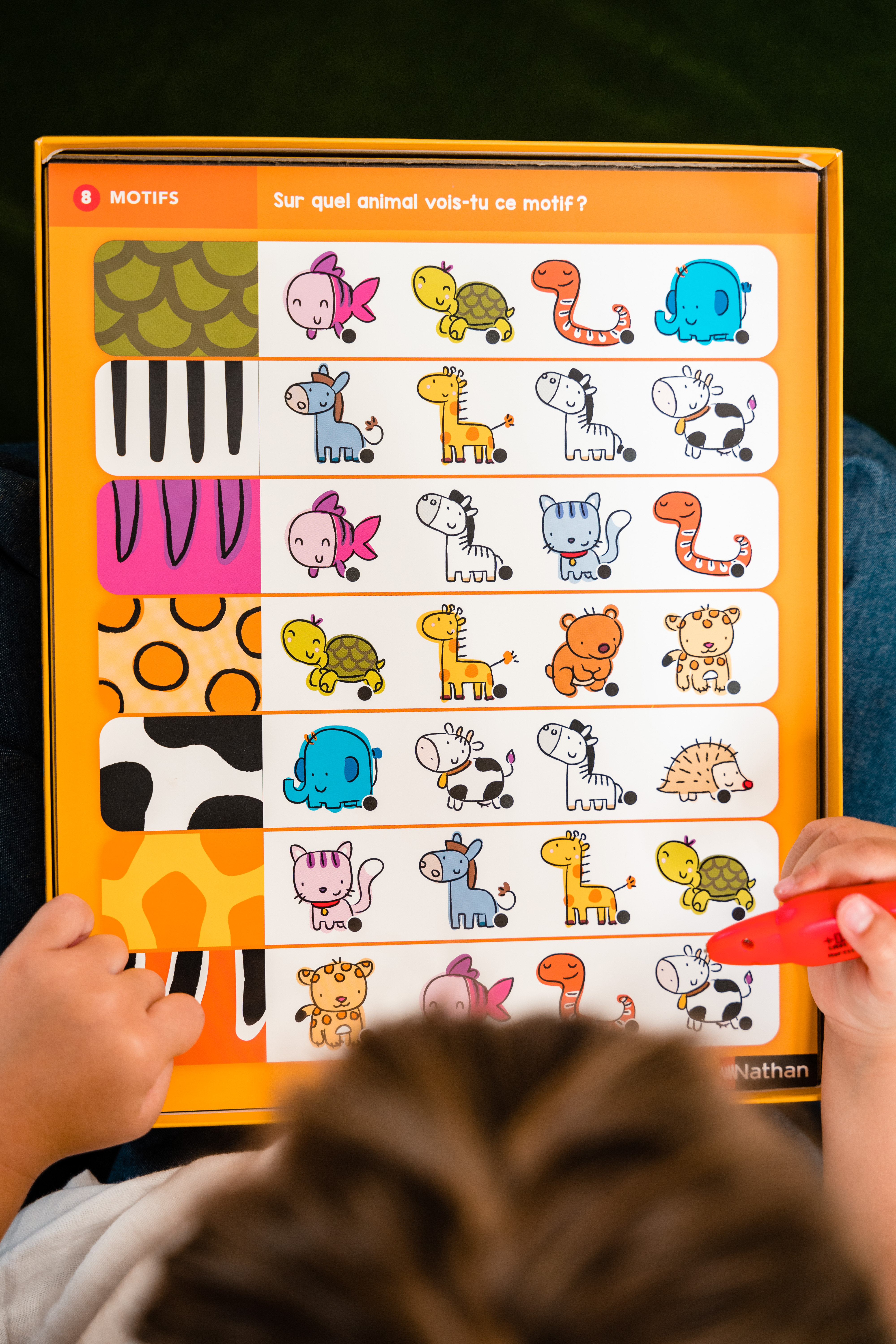 Un niño juega con un juego educativo con varios patrones de animales.