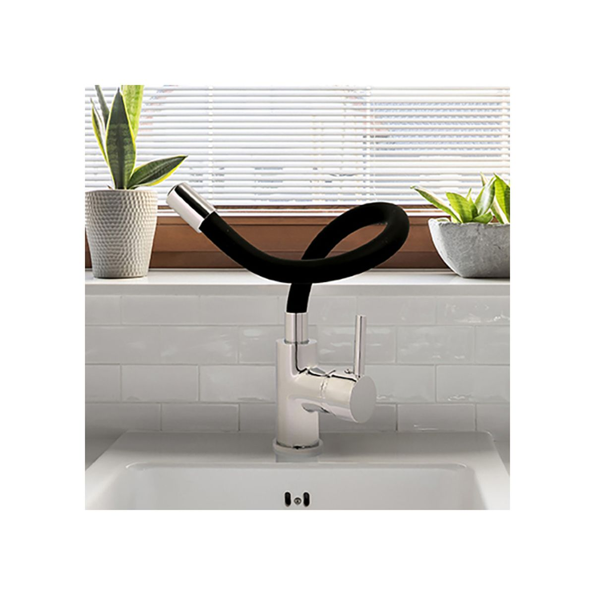 Rubinetto cromato con tubo nero flessibile su lavabo bianco. Due piante in vaso.
