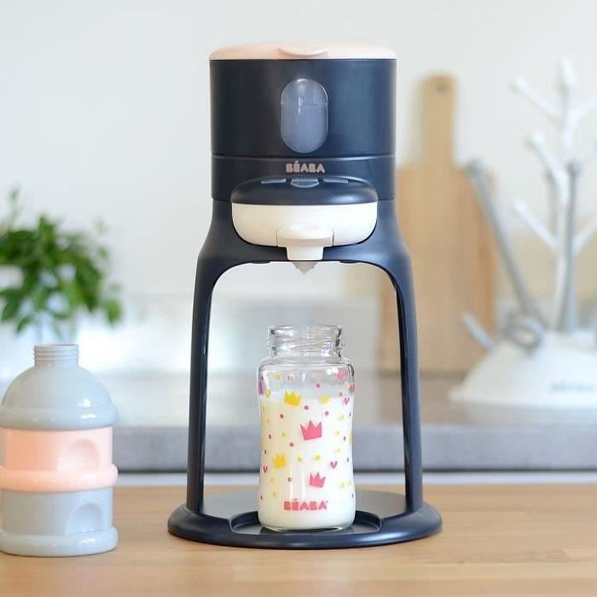 Ein Beaba-Flaschenzubereiter mit einer gefüllten Flasche und einem Milchpulverspender.