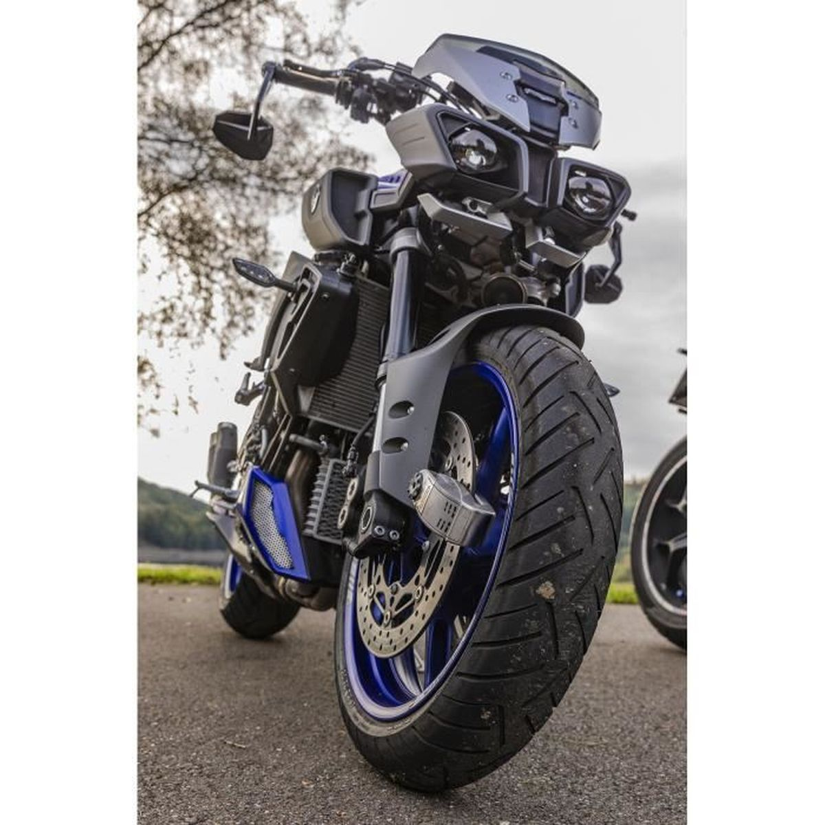 Ein dunkles Motorrad mit blauen Felgen steht draußen auf Asphalt.