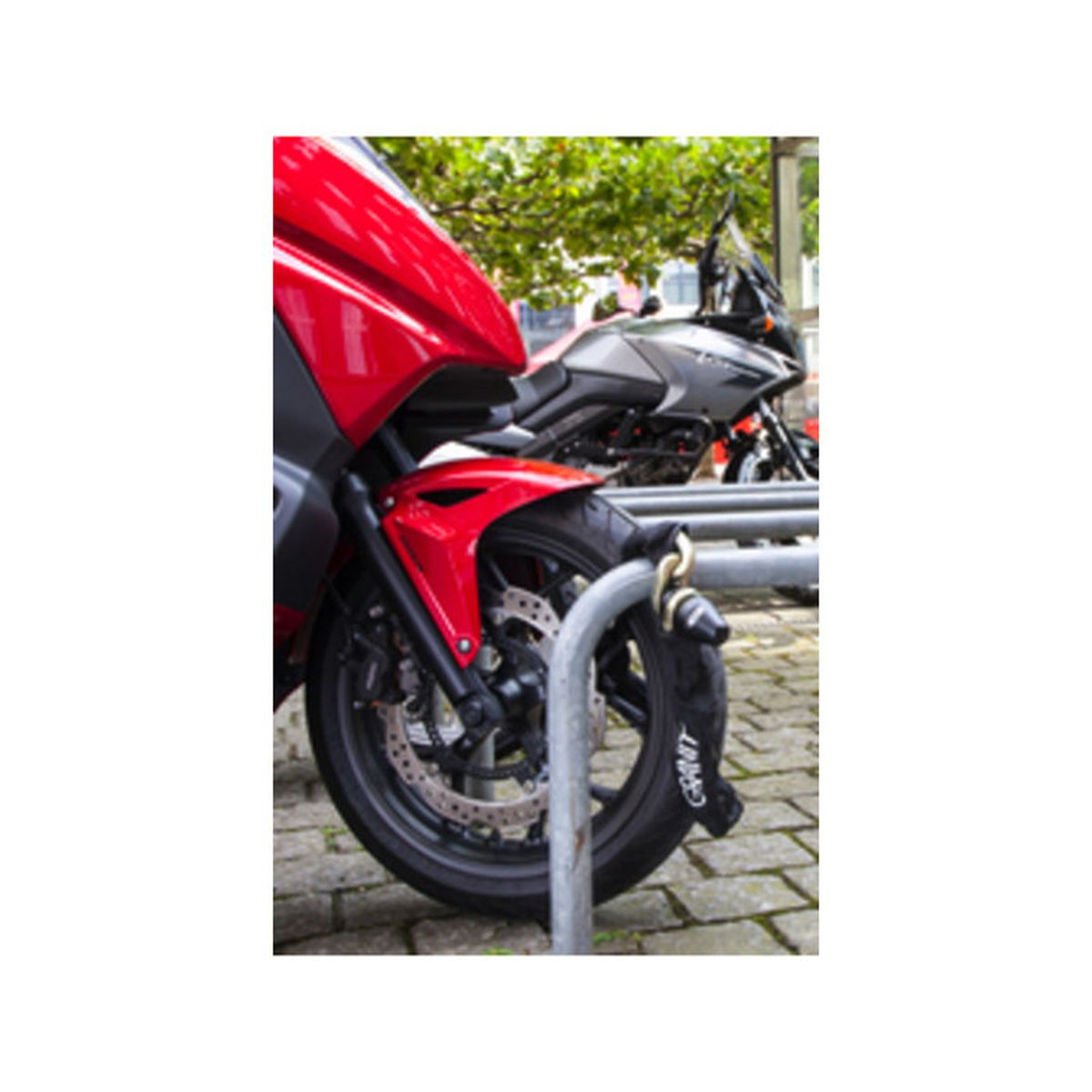 Rotes und graues Motorrad mit Schloss an einem Bügel gesichert.