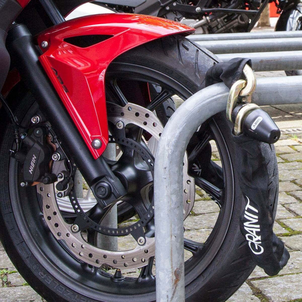 Rotes Motorradrad mit Schloss, das an einem Metallständer befestigt ist.