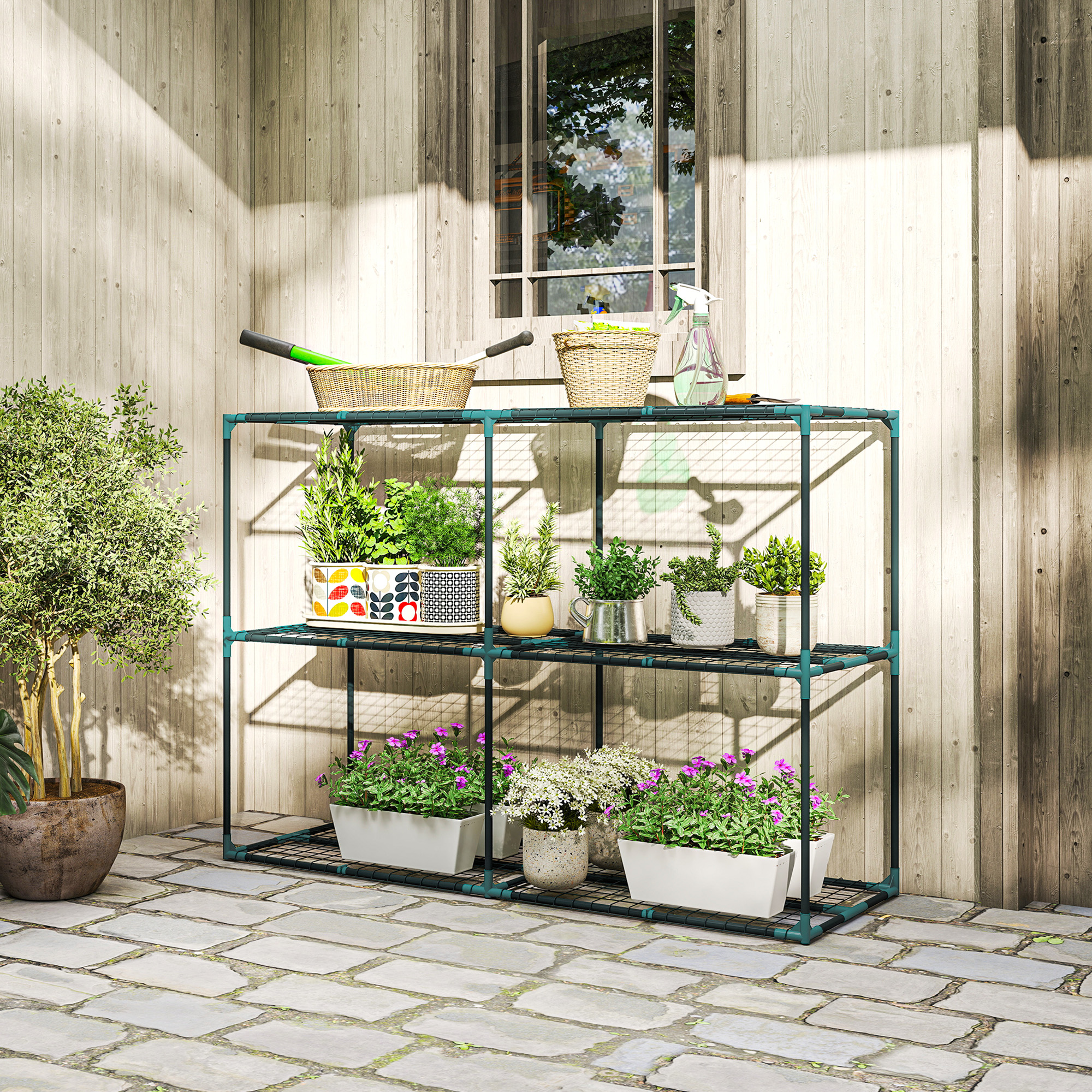 Una scaffalatura verde con piante si trova su un patio di pietra contro un muro di legno.