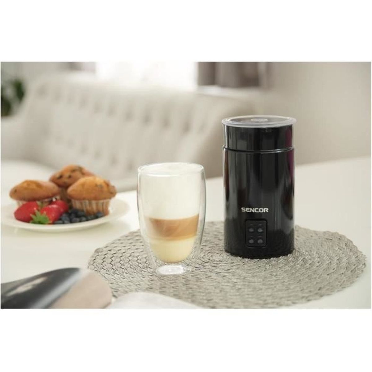 Ein schwarzer Milchaufschäumer steht neben einem Glas Latte Macchiato.