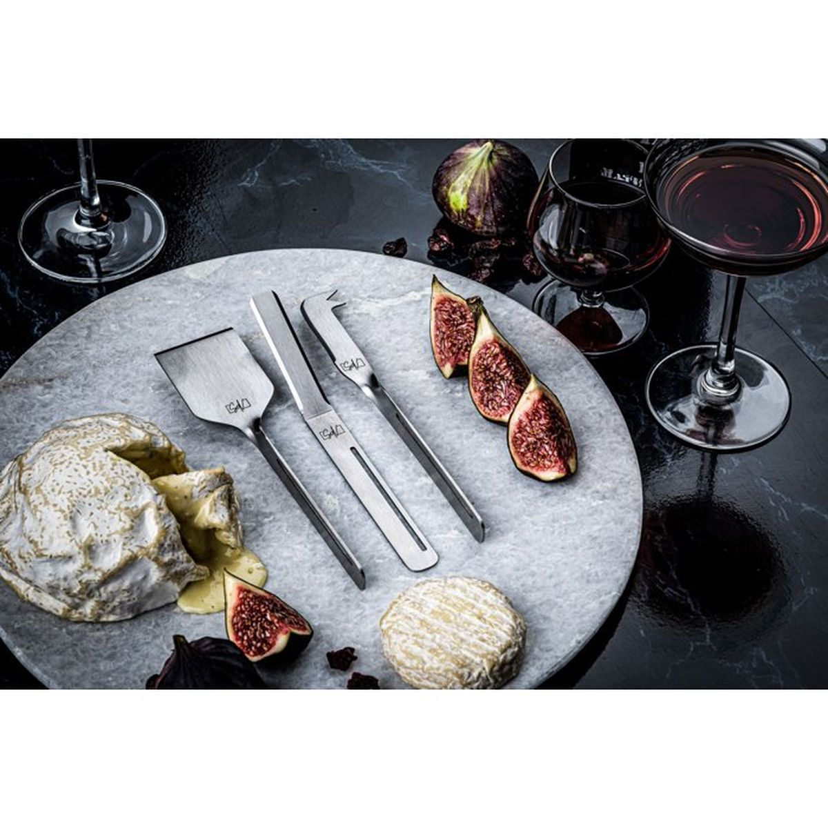 Tabla de quesos con Camembert, queso de cabra, higos, vino y herramientas.