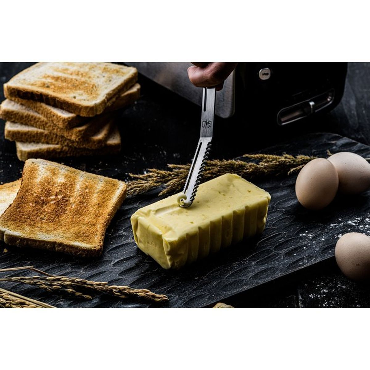 Un cuchillo corta mantequilla, con tostadas y huevos cerca.