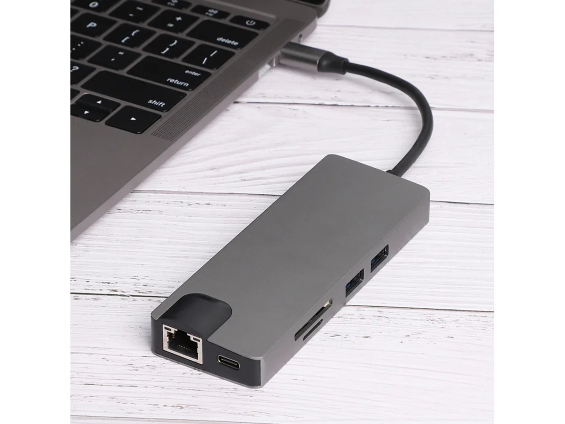 Ein grauer USB-C-Hub mit Ethernet-Anschluss, USB-Ports und Kartensteckplätzen ist mit einem Laptop verbunden.