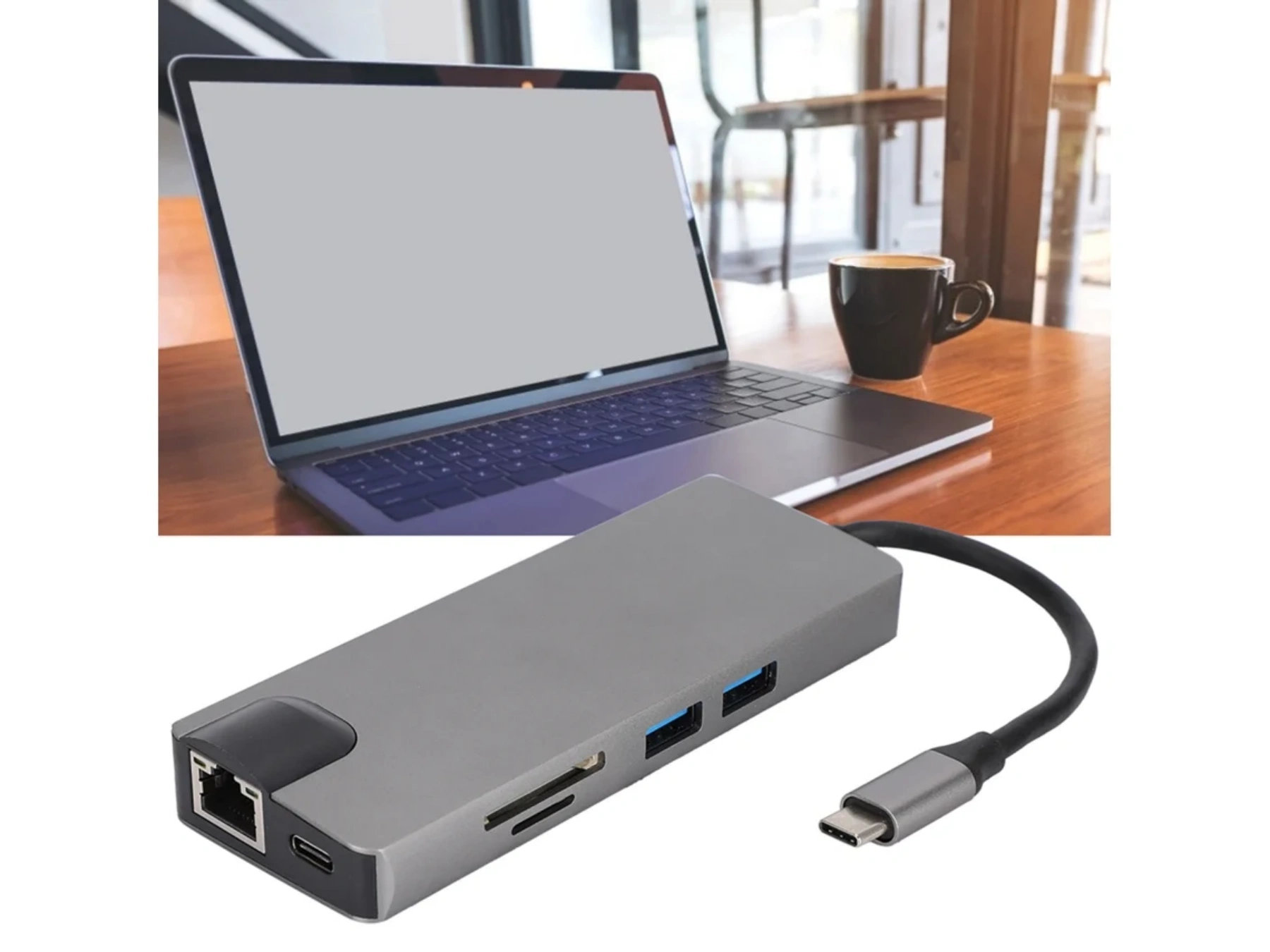 Grauer USB-C-Hub mit Anschlüssen und Kabel neben einem Laptop und einer Kaffeetasse.