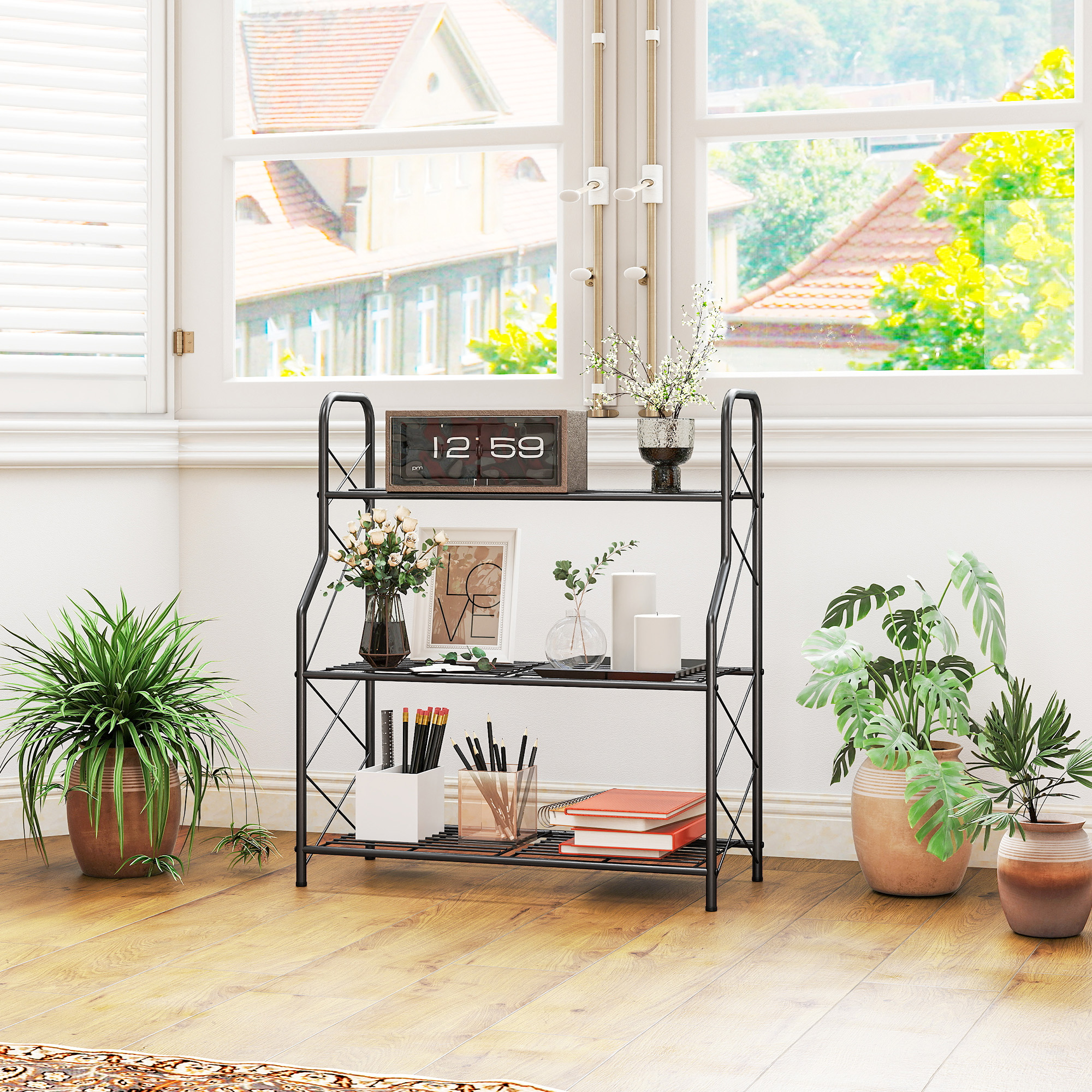 Un estante negro con plantas, libros y objetos decorativos frente a una ventana.