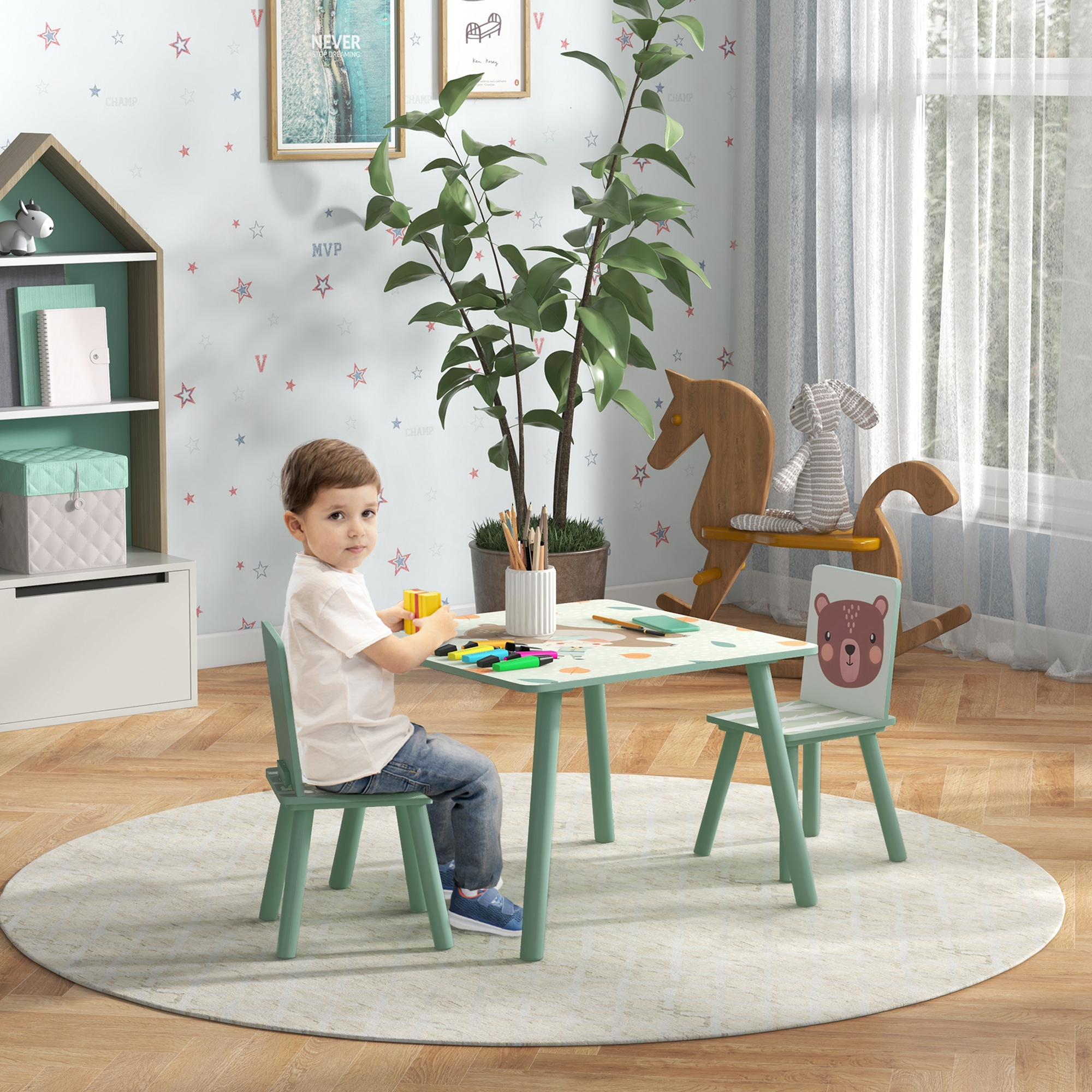 Un niño pequeño se sienta en una mesa infantil verde con un caballito de madera.