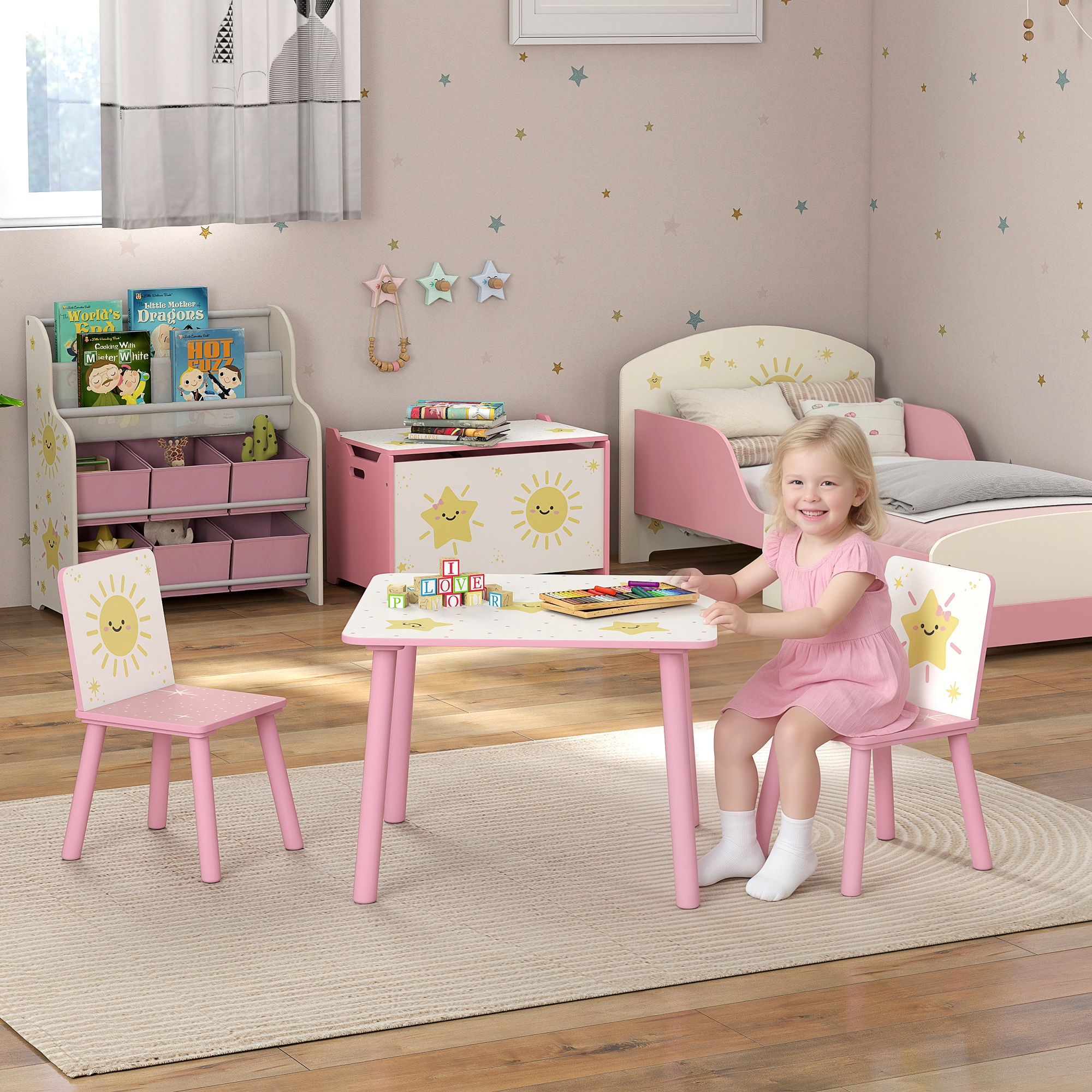 Una bambina siede a un tavolo rosa con sedie, giocattoli e un letto sullo sfondo.