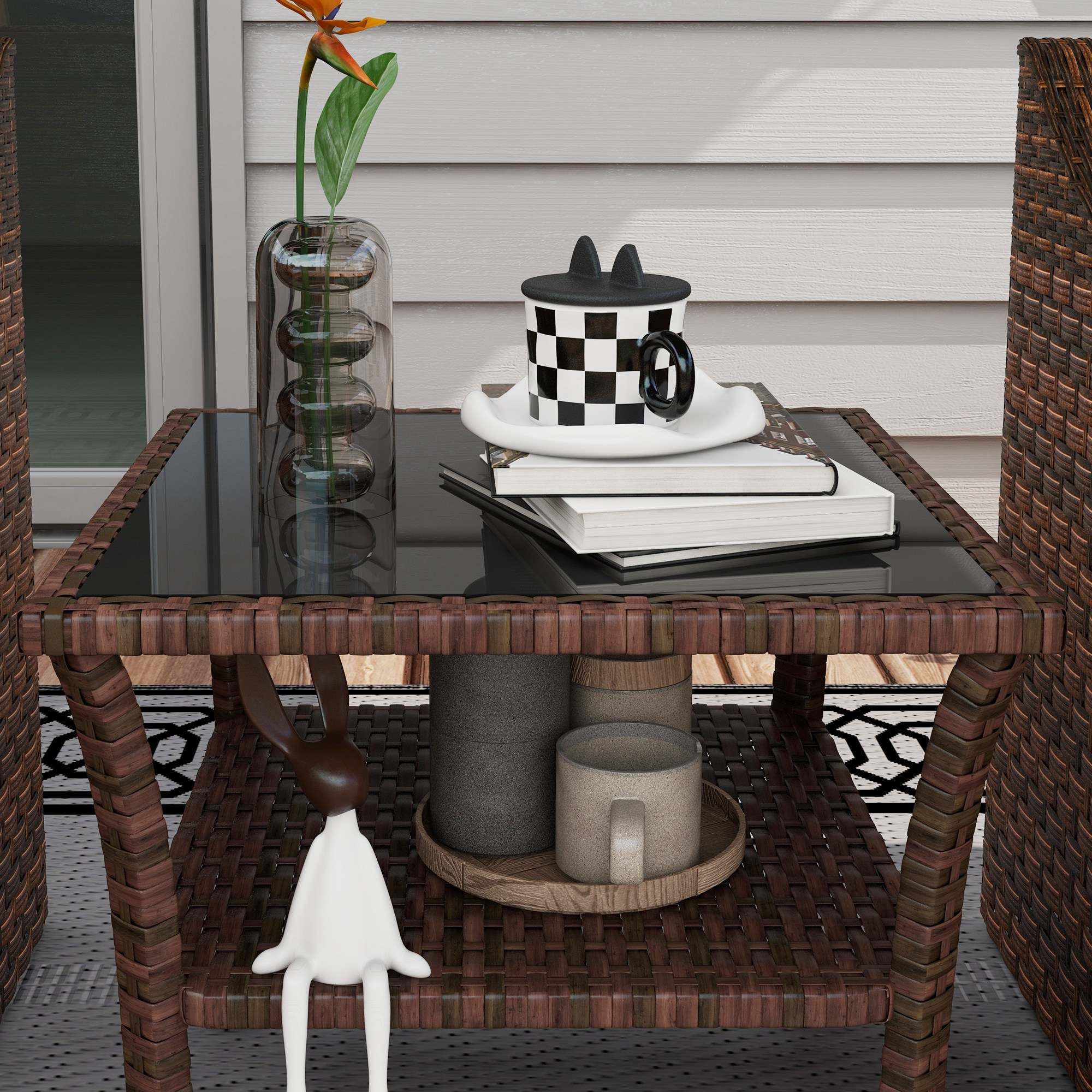 Mesa de mimbre con tapa de cristal, decorada con flor, taza y libros.