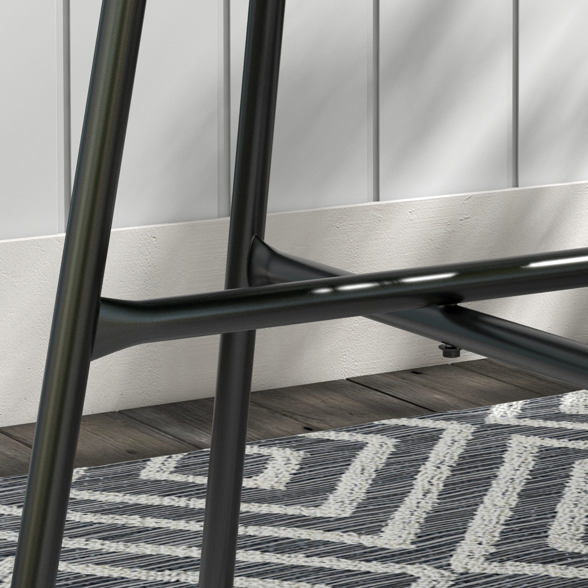 Patas metálicas negras de mueble sobre suelo de madera con alfombra.