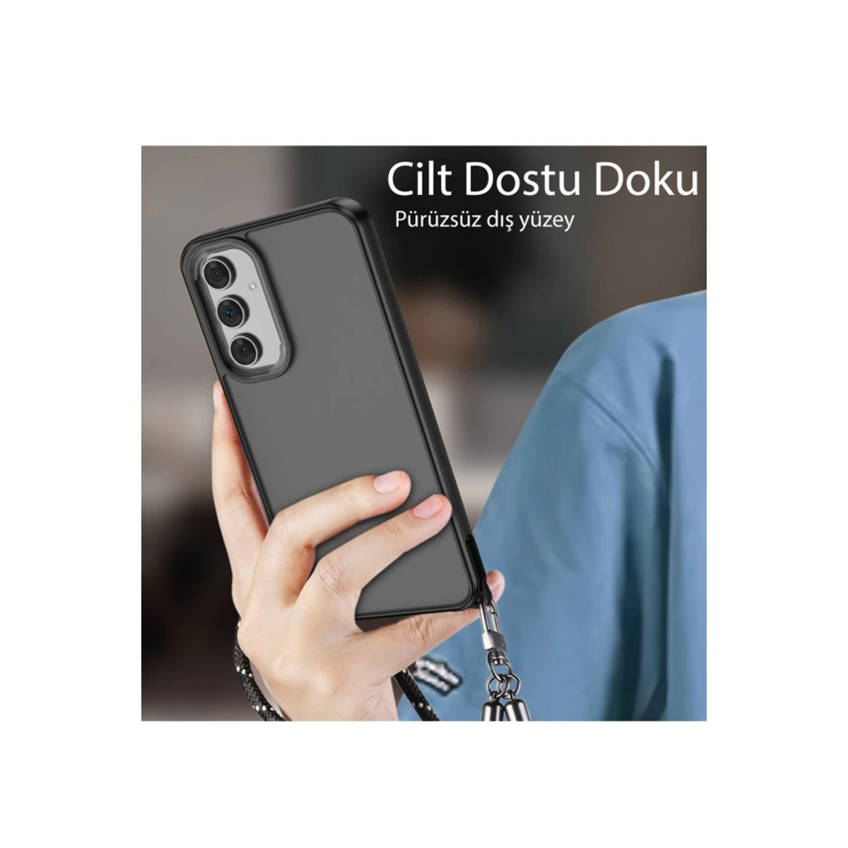 Elde kameralı siyah telefon, kordonuna takılı. Arkada mavi kıyafet.