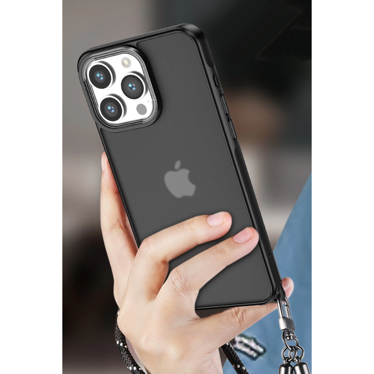 Dört kameralı siyah iPhone, elde tutuluyor. Bir kordon takılı.