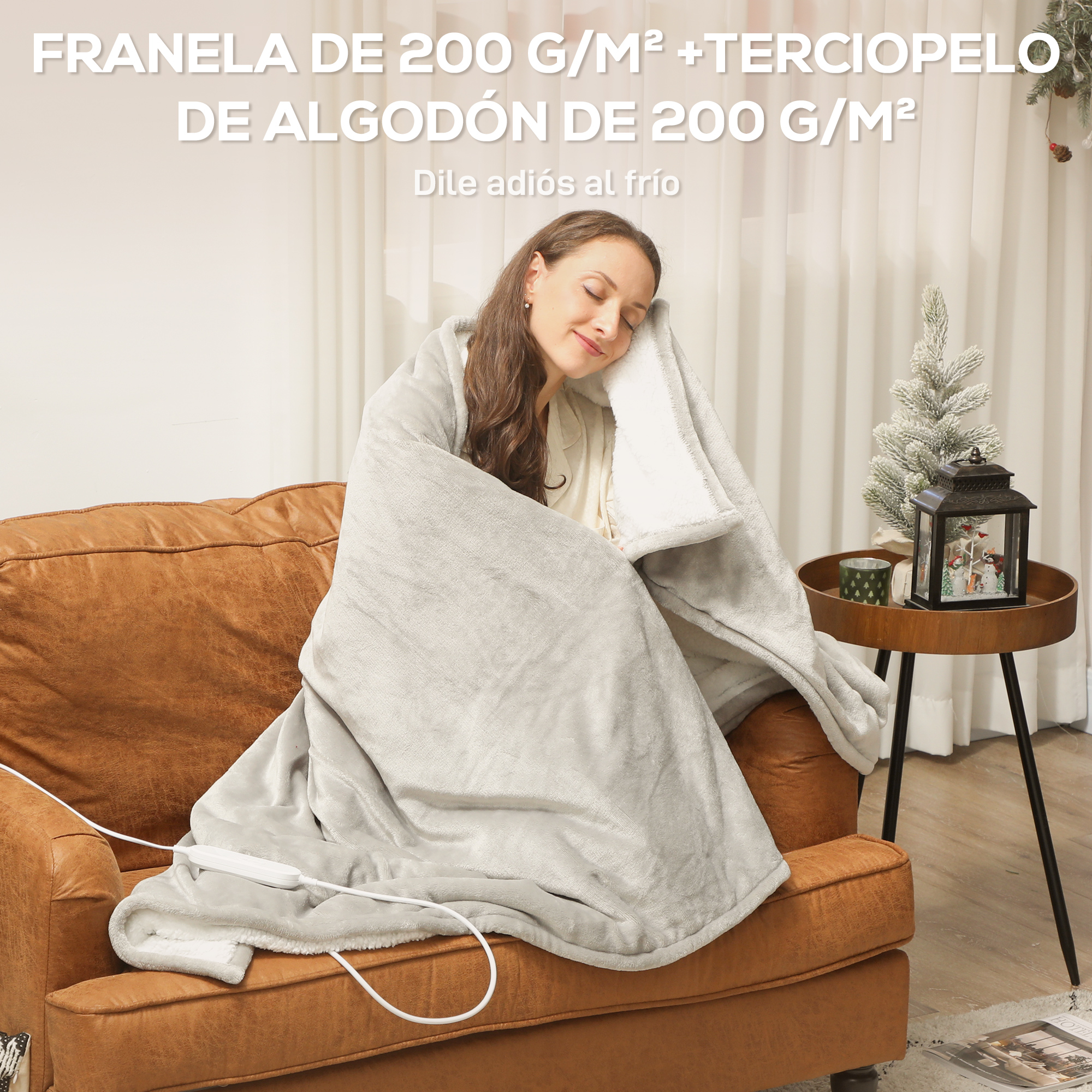Una mujer sentada en un sofá marrón, envuelta en una manta gris suave con forro blanco.
