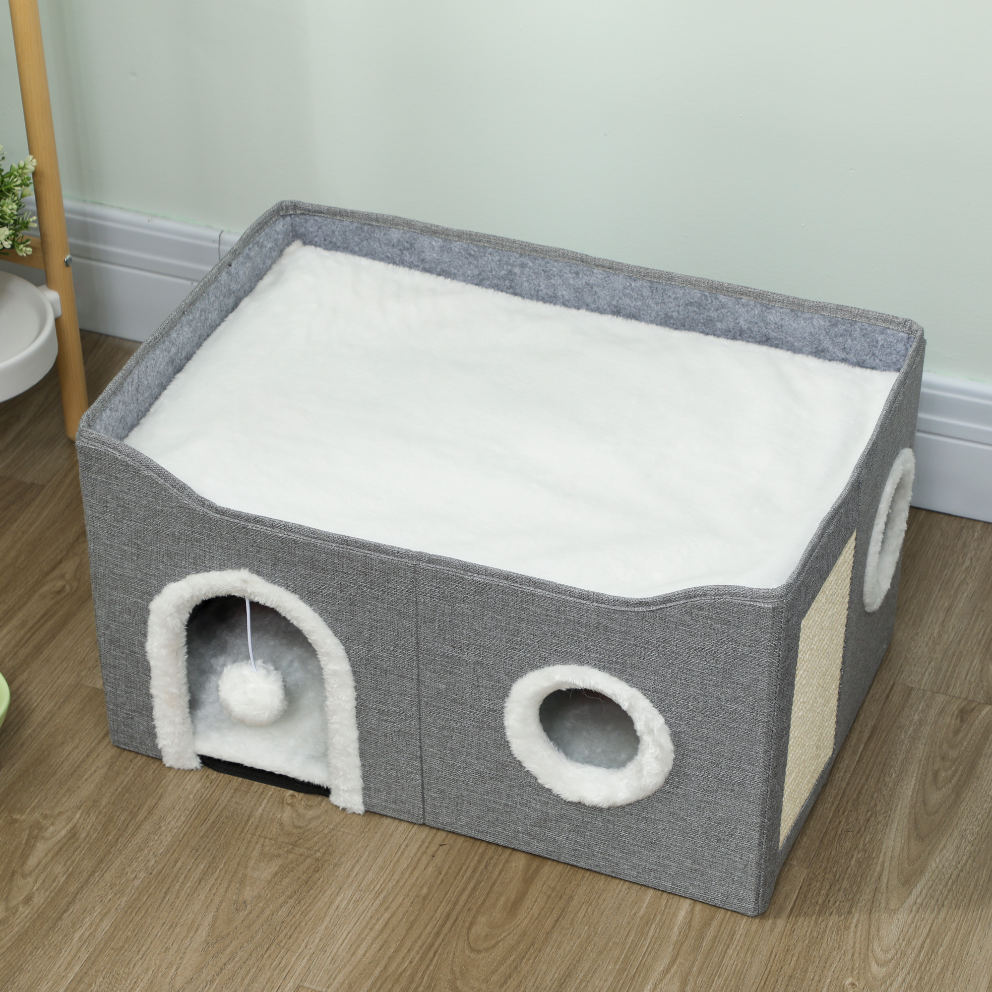 Casa gris para gatos con cojín blanco y aberturas redondas.