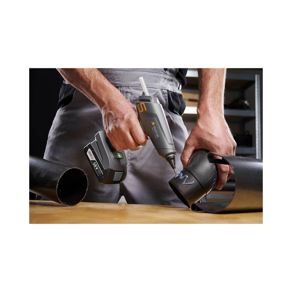 Un homme utilise un pistolet à colle chaude sans fil pour joindre deux tuyaux.