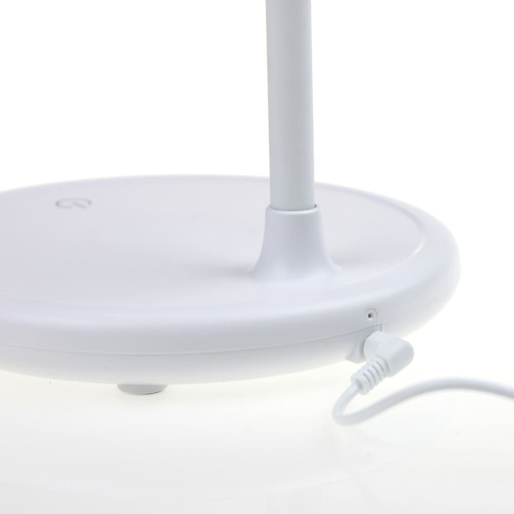 Primer plano de una lámpara blanca con el cable de carga enchufado.
