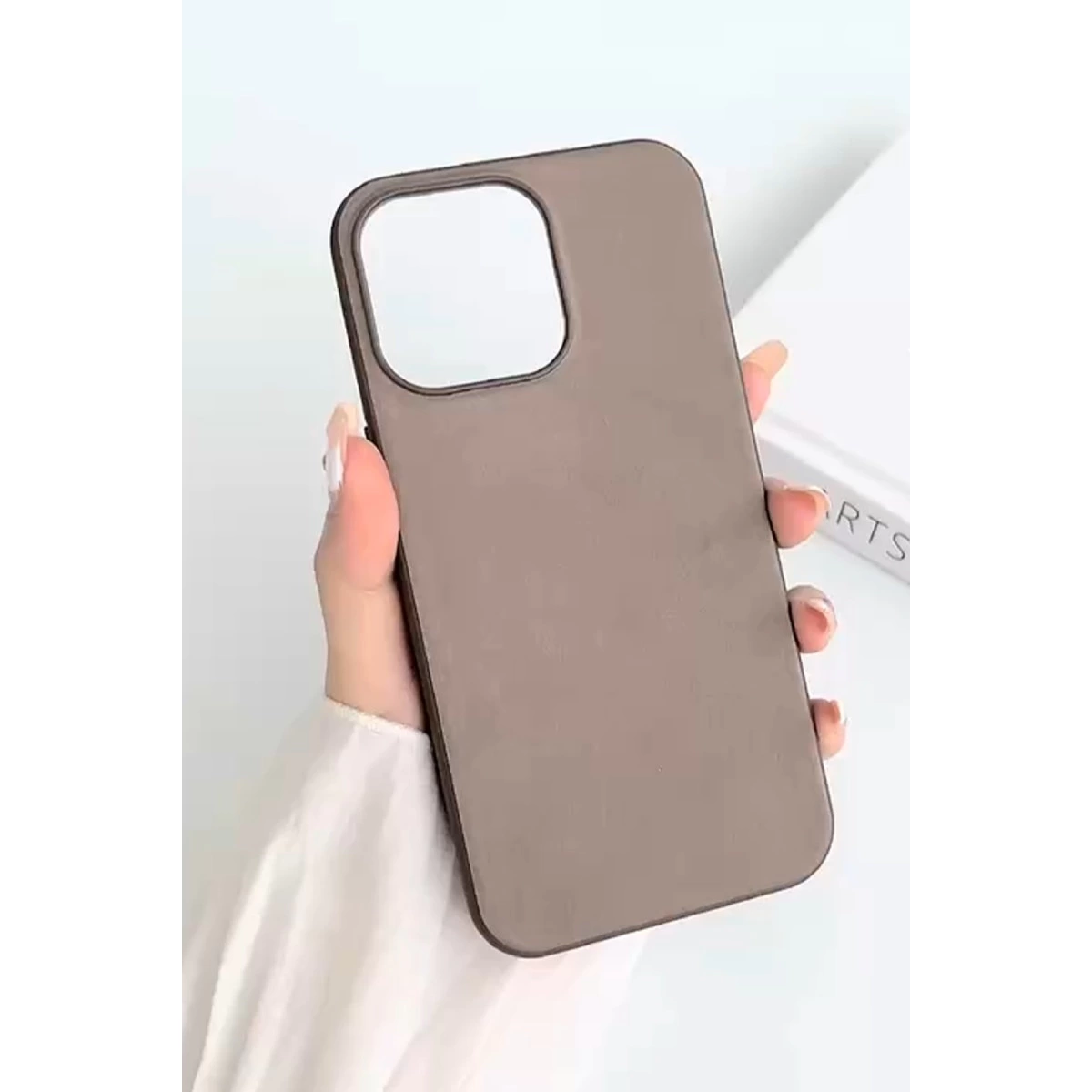 Bir el, kamera açıklığı olan kahverengi telefon kılıfı tutuyor.